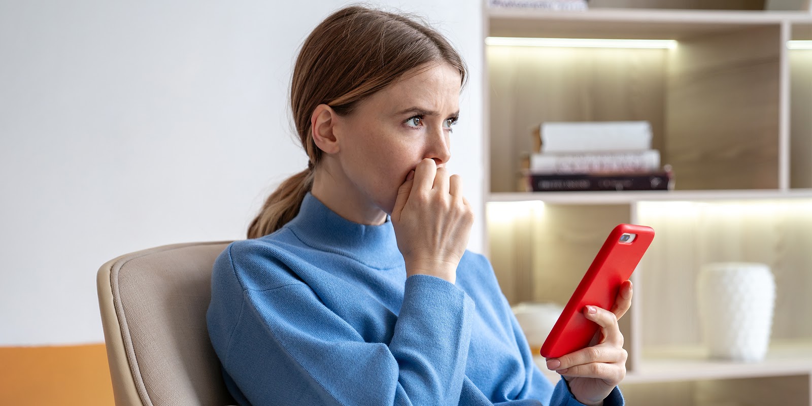 Une femme pensive assise avec un téléphone à la main | Source : Shutterstock