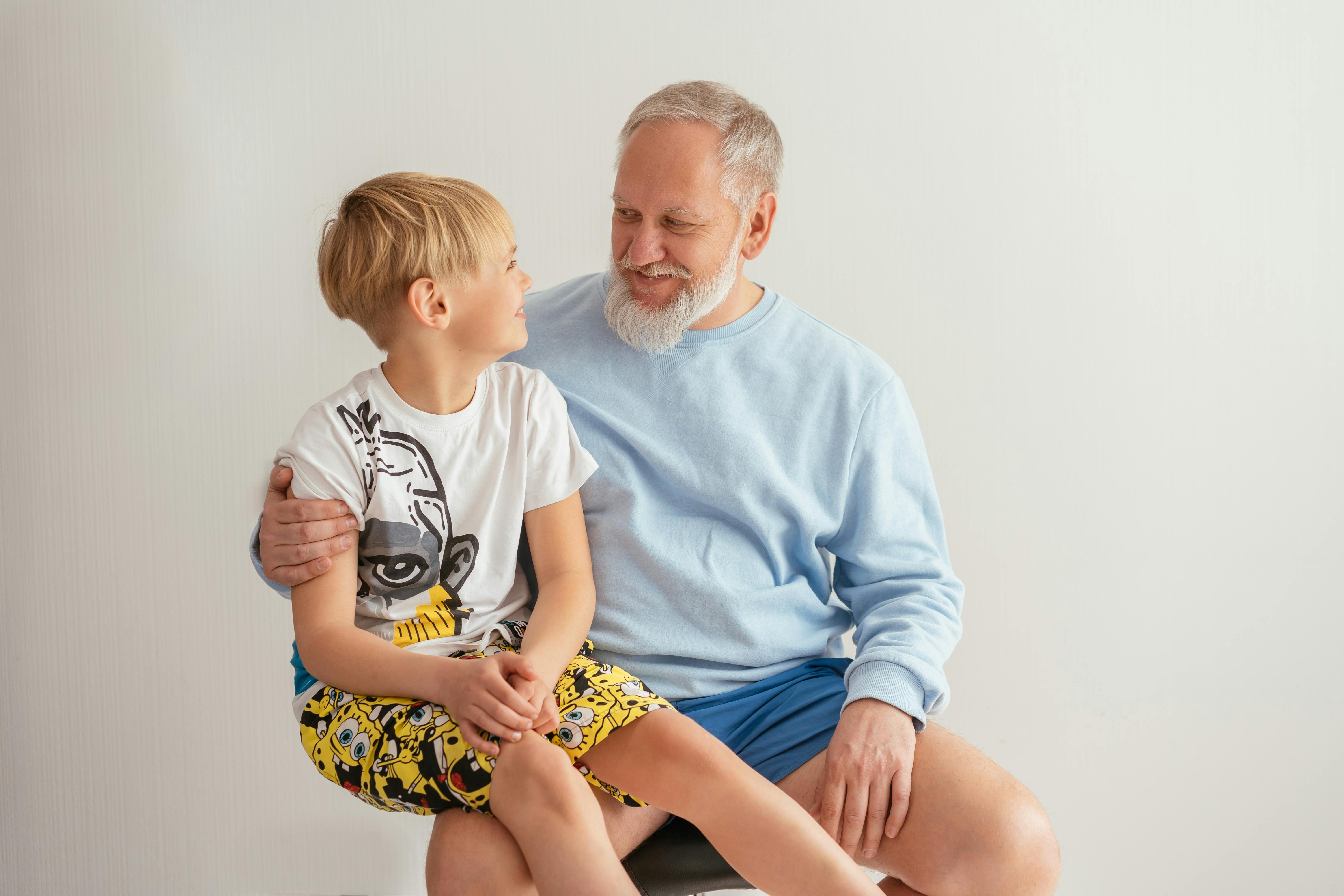 Jeune garçon assis sur les genoux de son grand-père | Source : Pexels