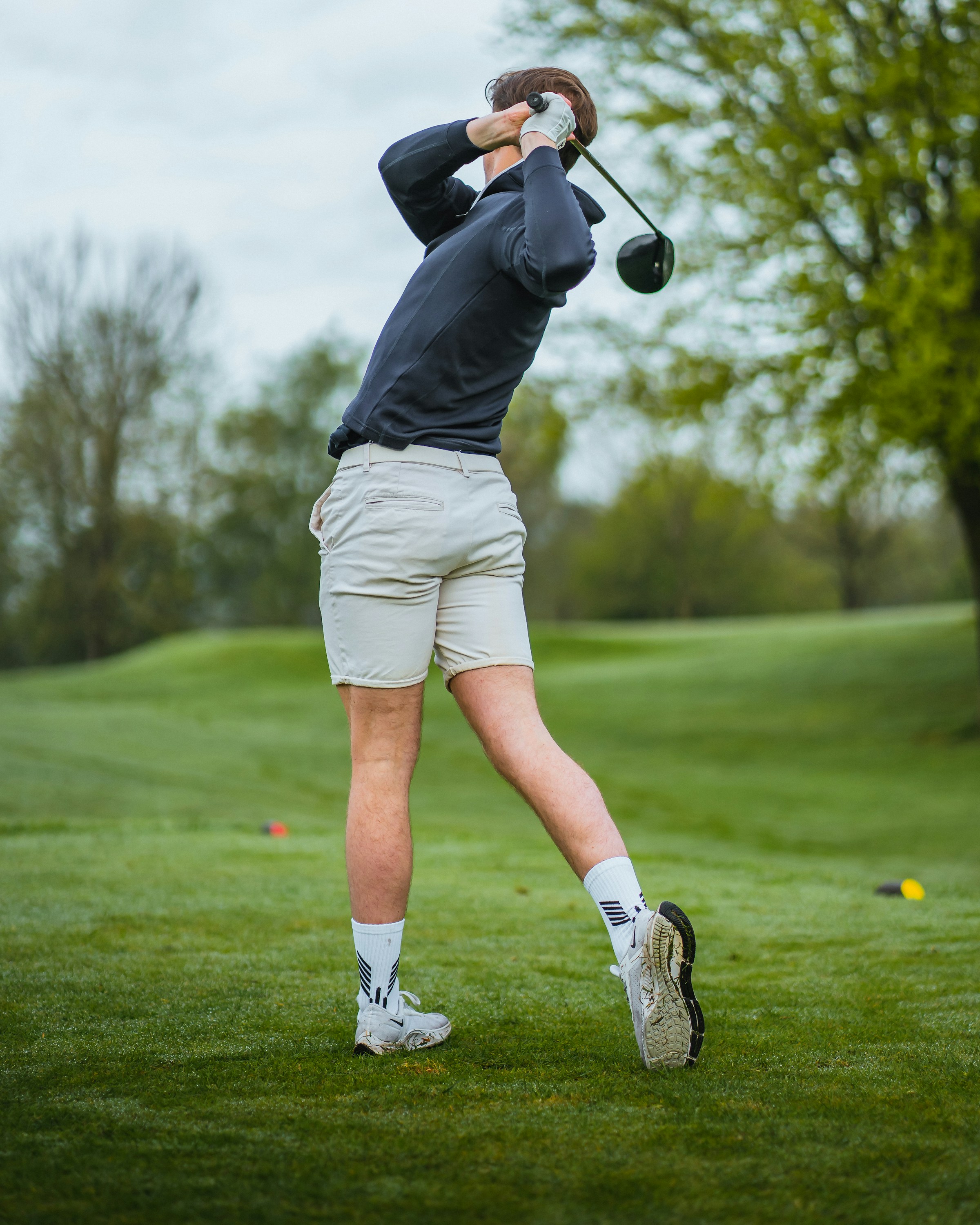 Un homme balançant un club de golf sur un terrain de golf | Source : Unsplash