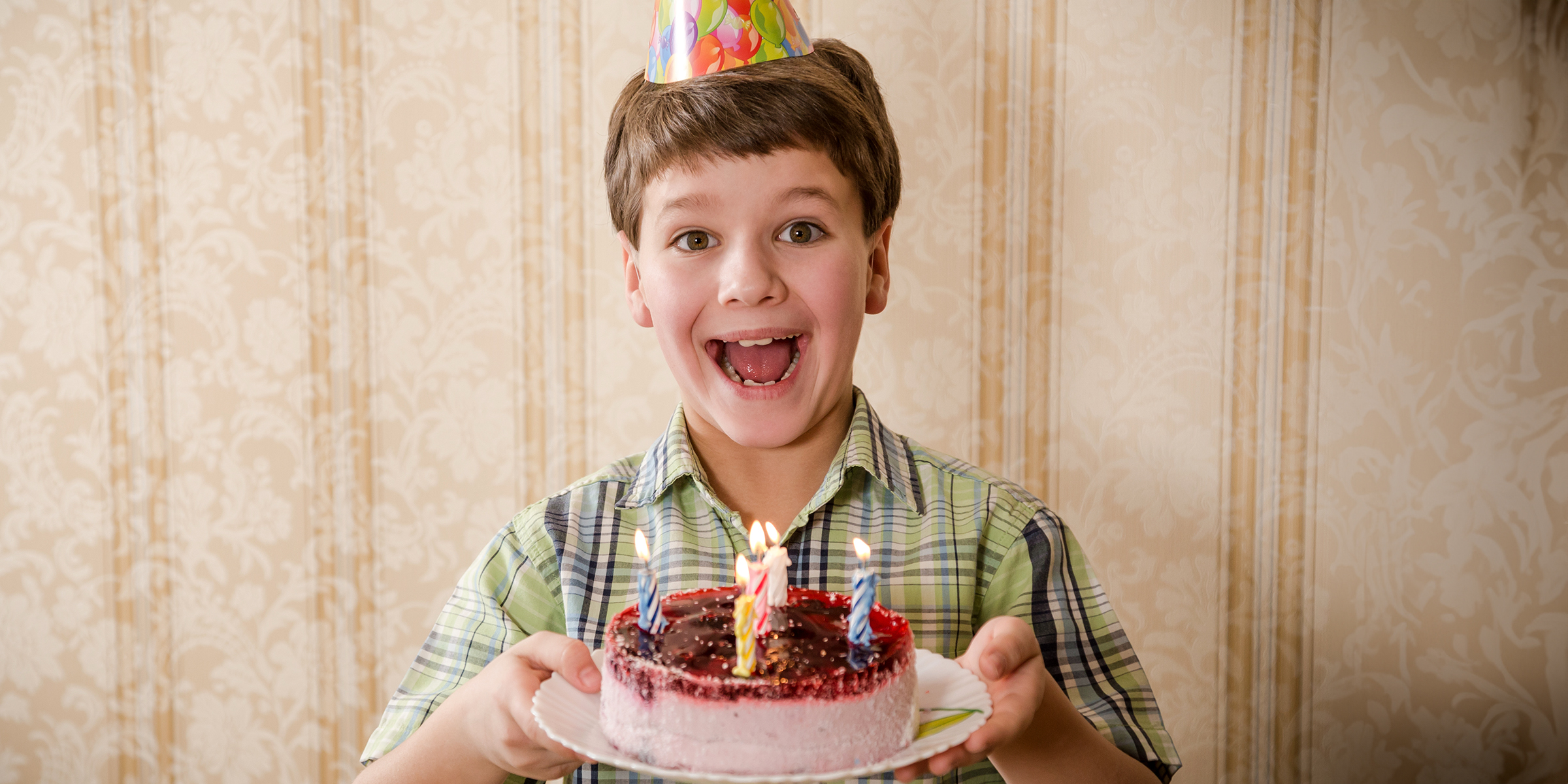 Un garçon tenant un gâteau d'anniversaire | Source : Shutterstock
