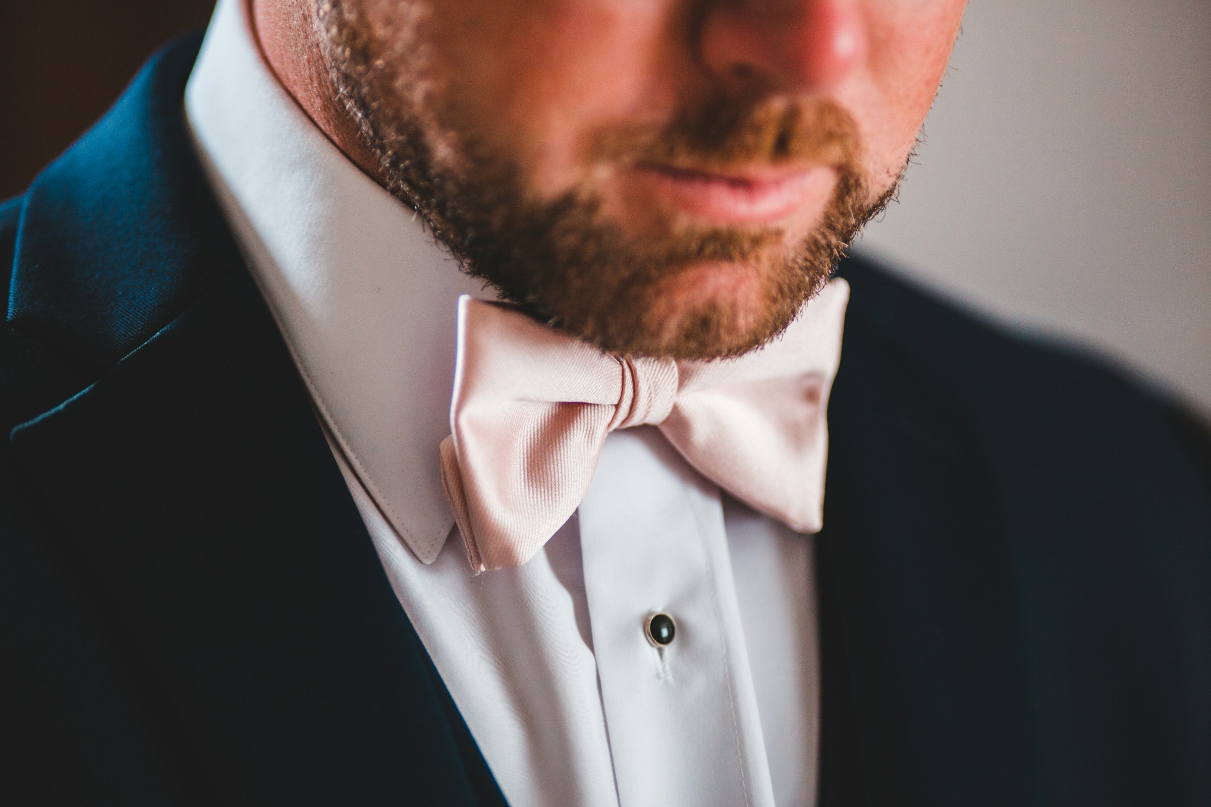 Un homme en smoking avec un nœud papillon rose | Source : Unsplash
