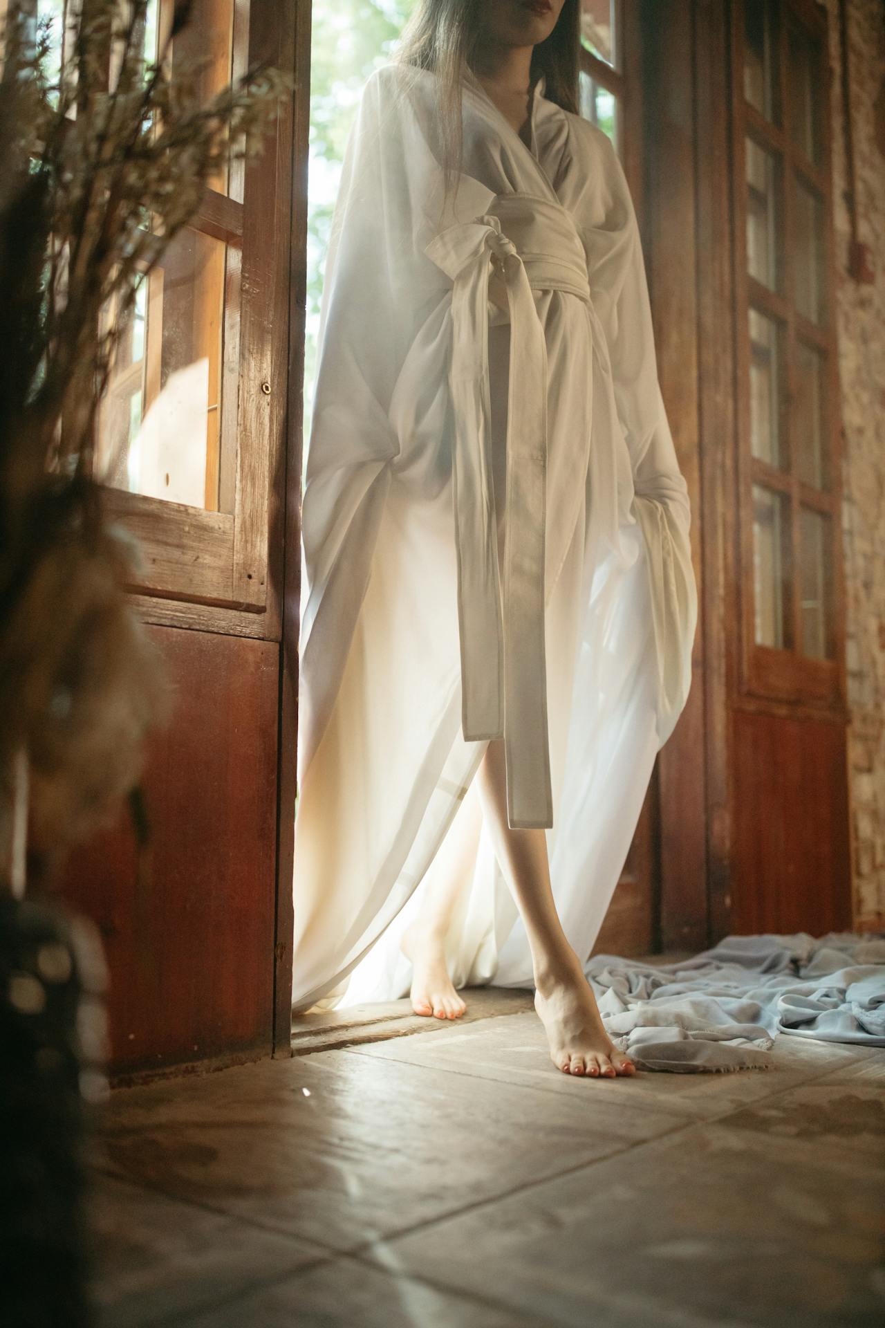 Une femme en robe blanche se tenant à l'entrée de la porte | Source : Pexels