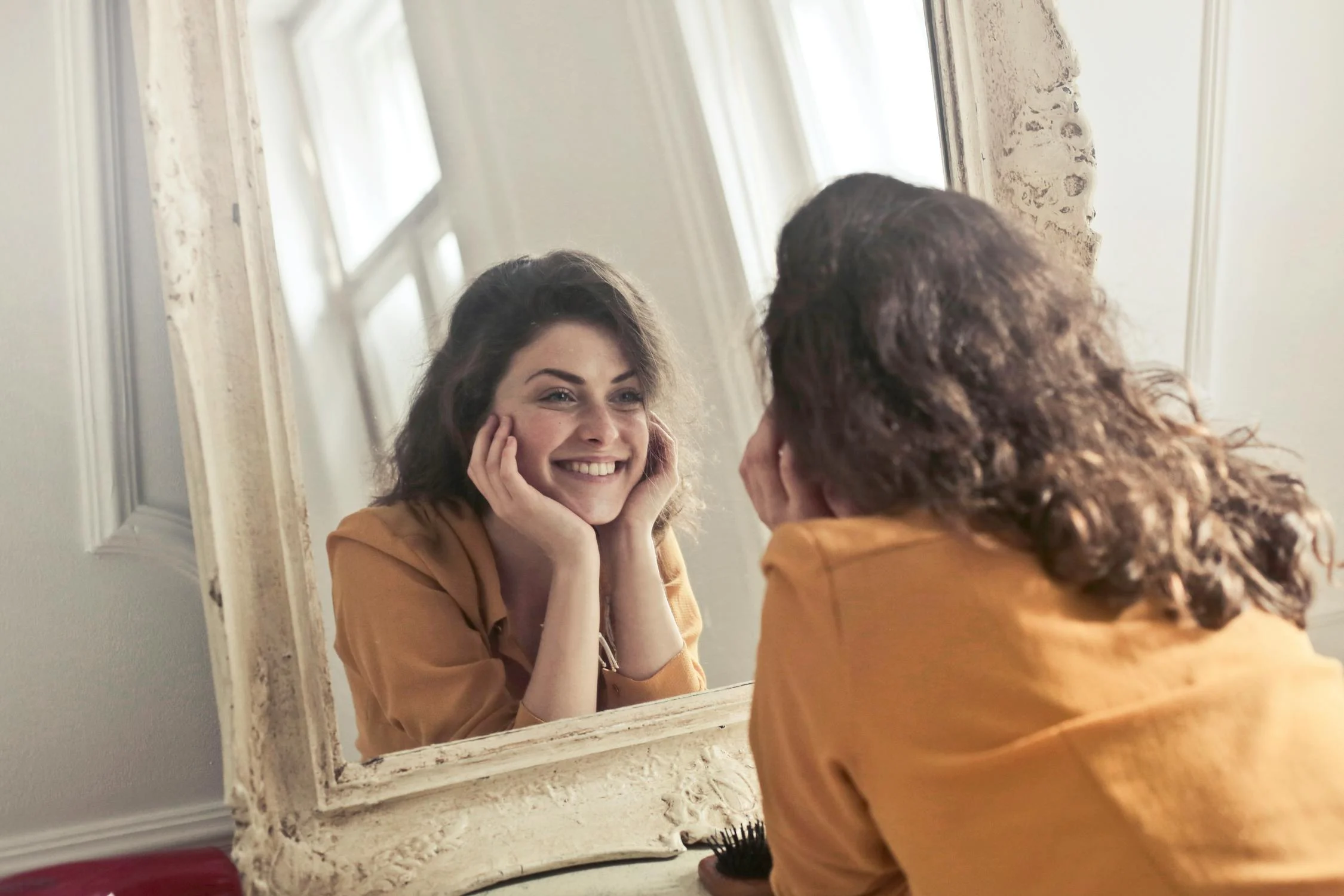 Une femme heureuse qui se regarde dans le miroir | Source : Pexels