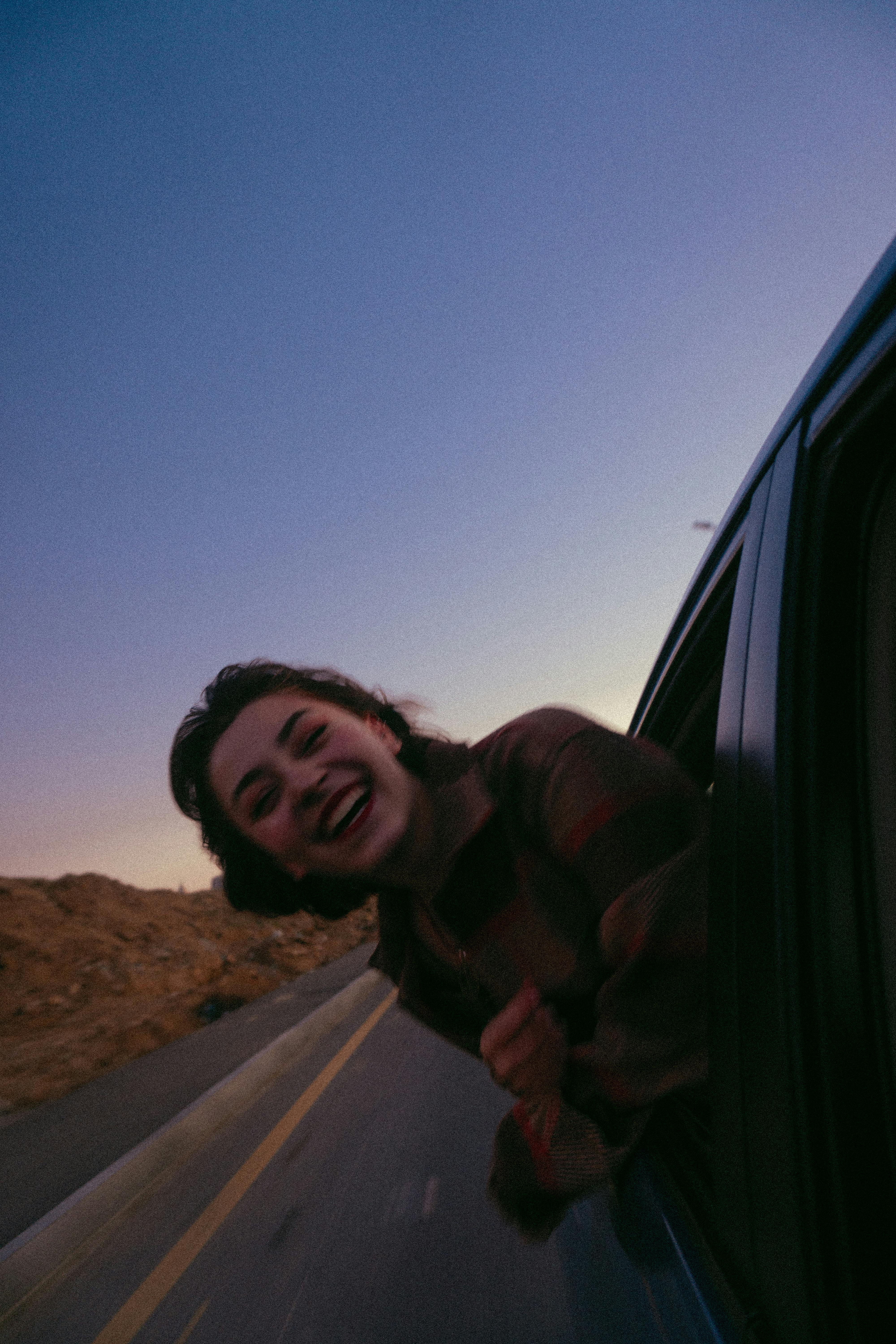 Une adolescente souriante, la tête par la fenêtre d'une voiture | Source : Pexels