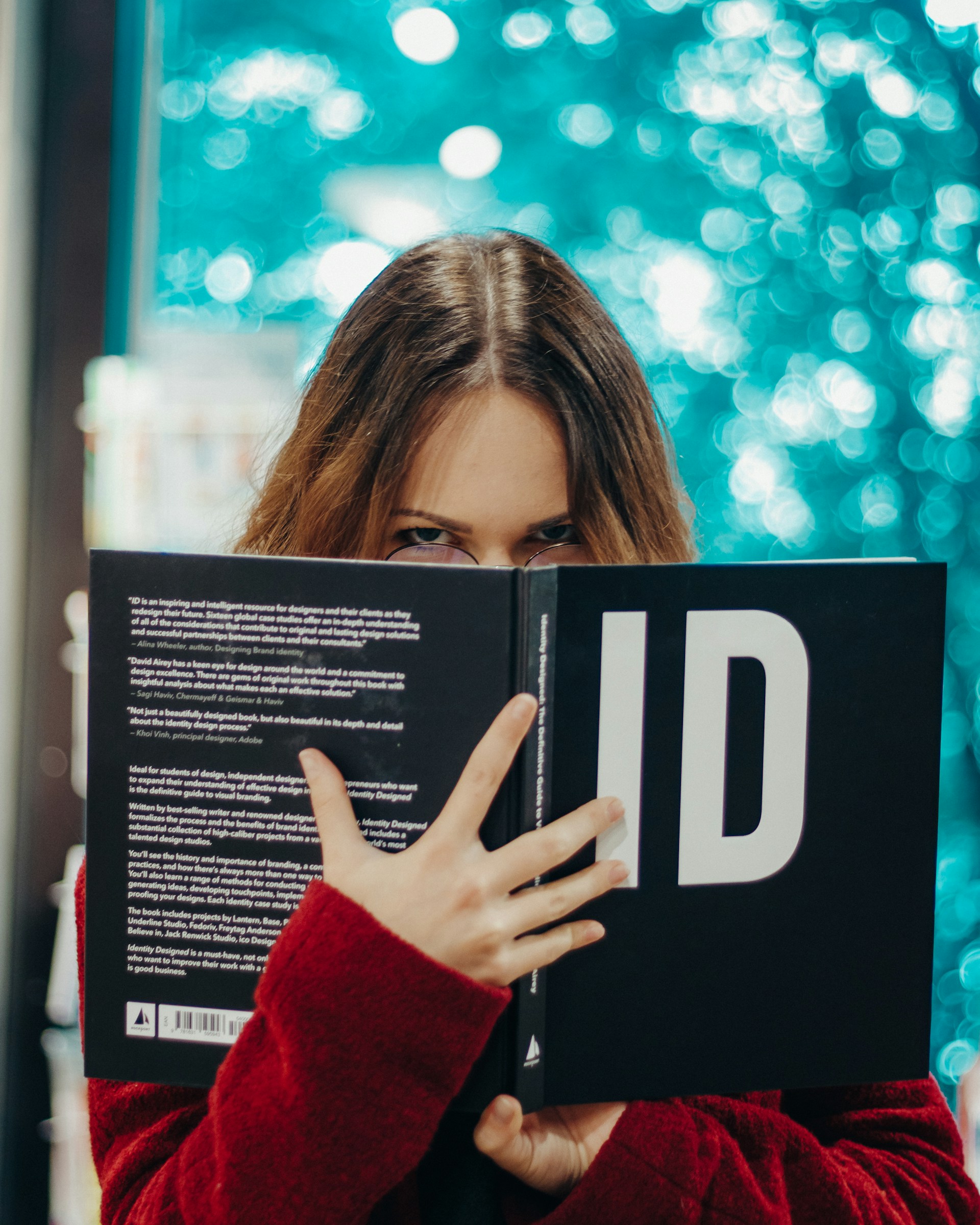 Une jeune femme tenant un livre et regardant fixement | Source : Unsplash