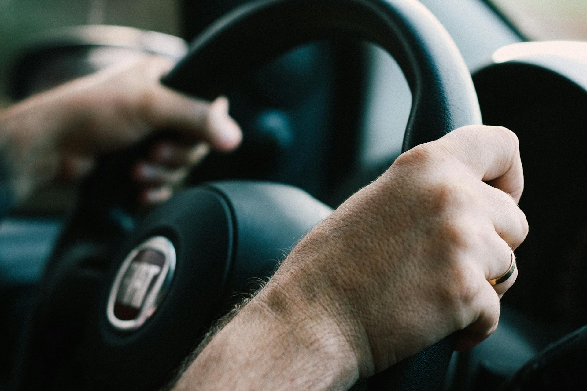 Gros plan sur les mains d'un homme saisissant fermement le volant | Source : Pexels