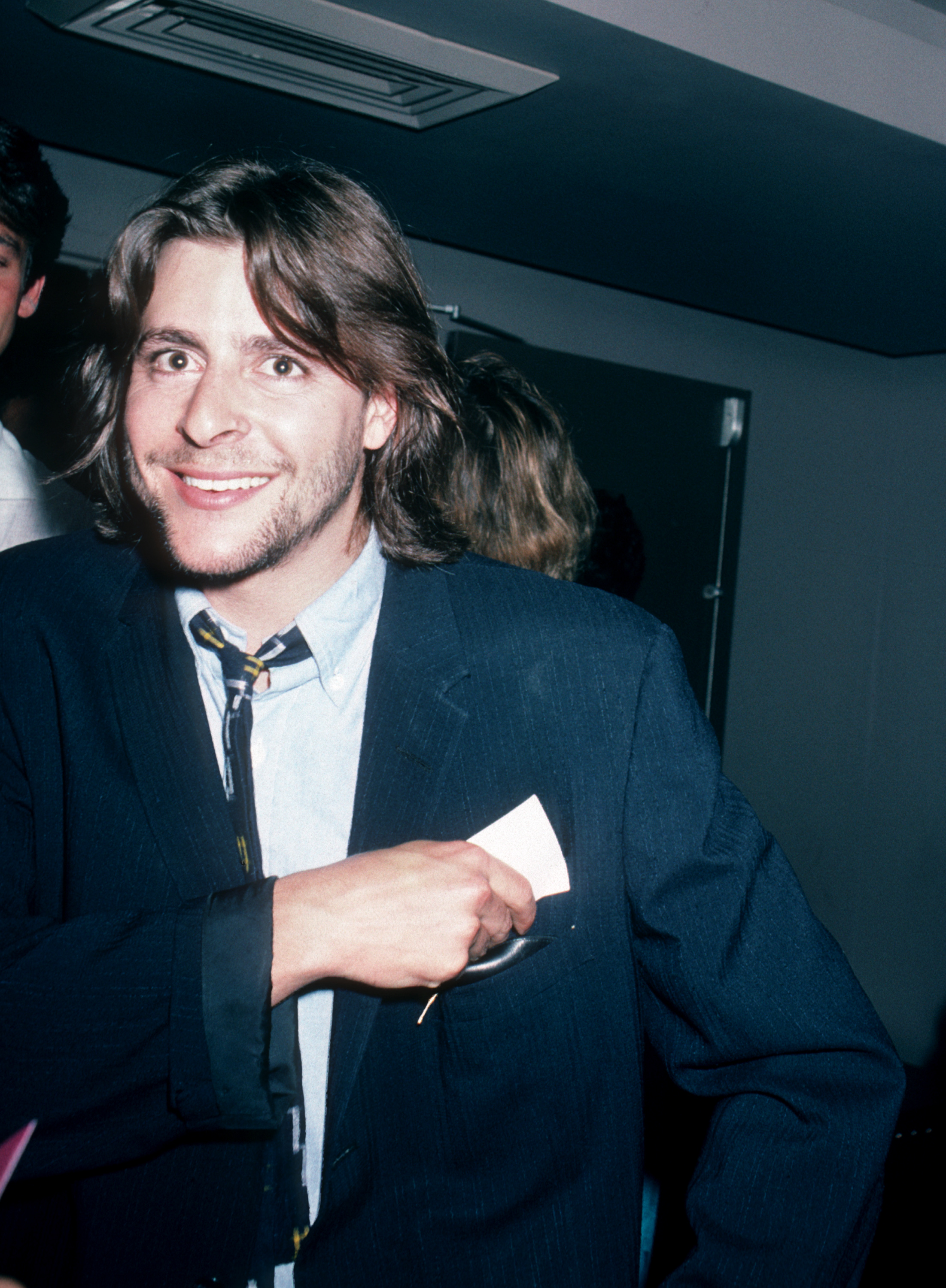 Avec un sourire chaleureux, tout en glissant une carte dans la poche de sa veste, le jeune acteur profitait d'une soirée à l'exposition d'art de Peter Max chez Marylou's, à New York, en 1986. | Source : Getty Images