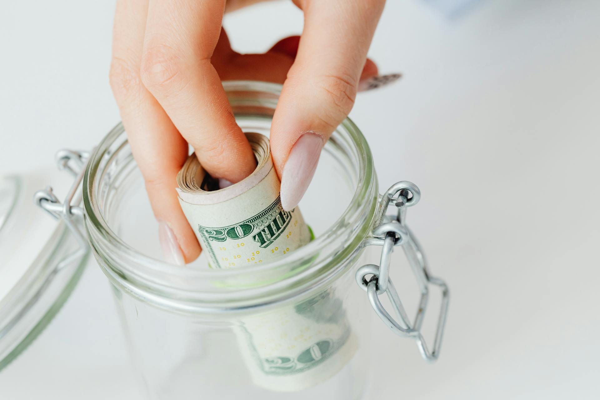 Une femme qui prend un rouleau de billets d'un dollar dans un bocal en verre | Source : Pexels