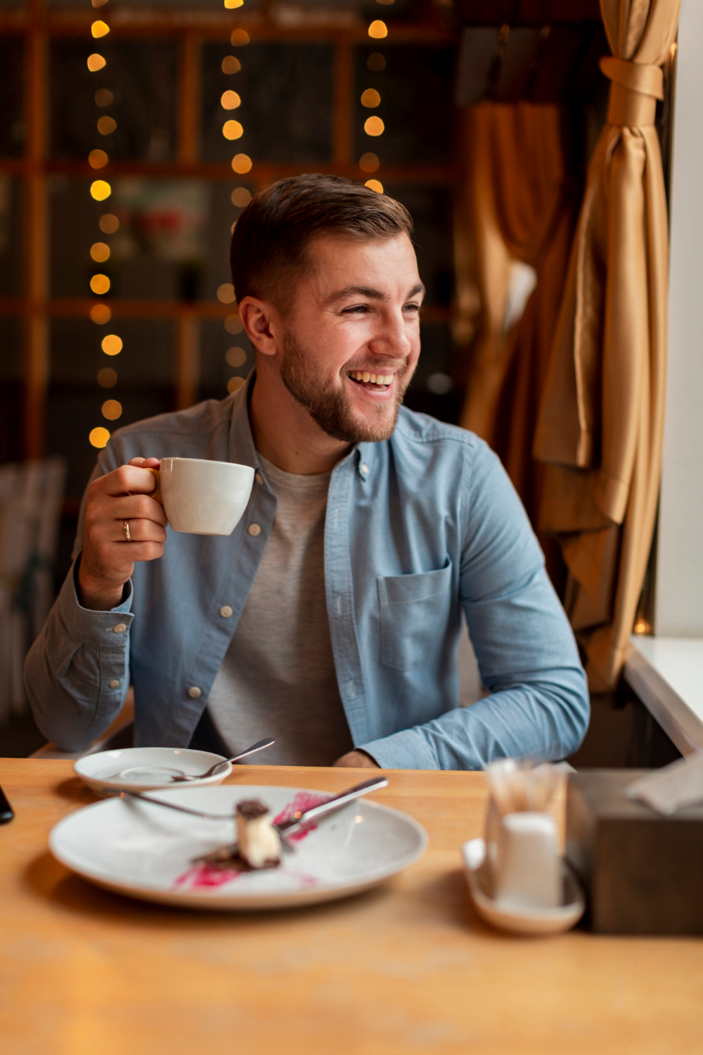 Un homme tenant une tasse et riant | Source : Freepik