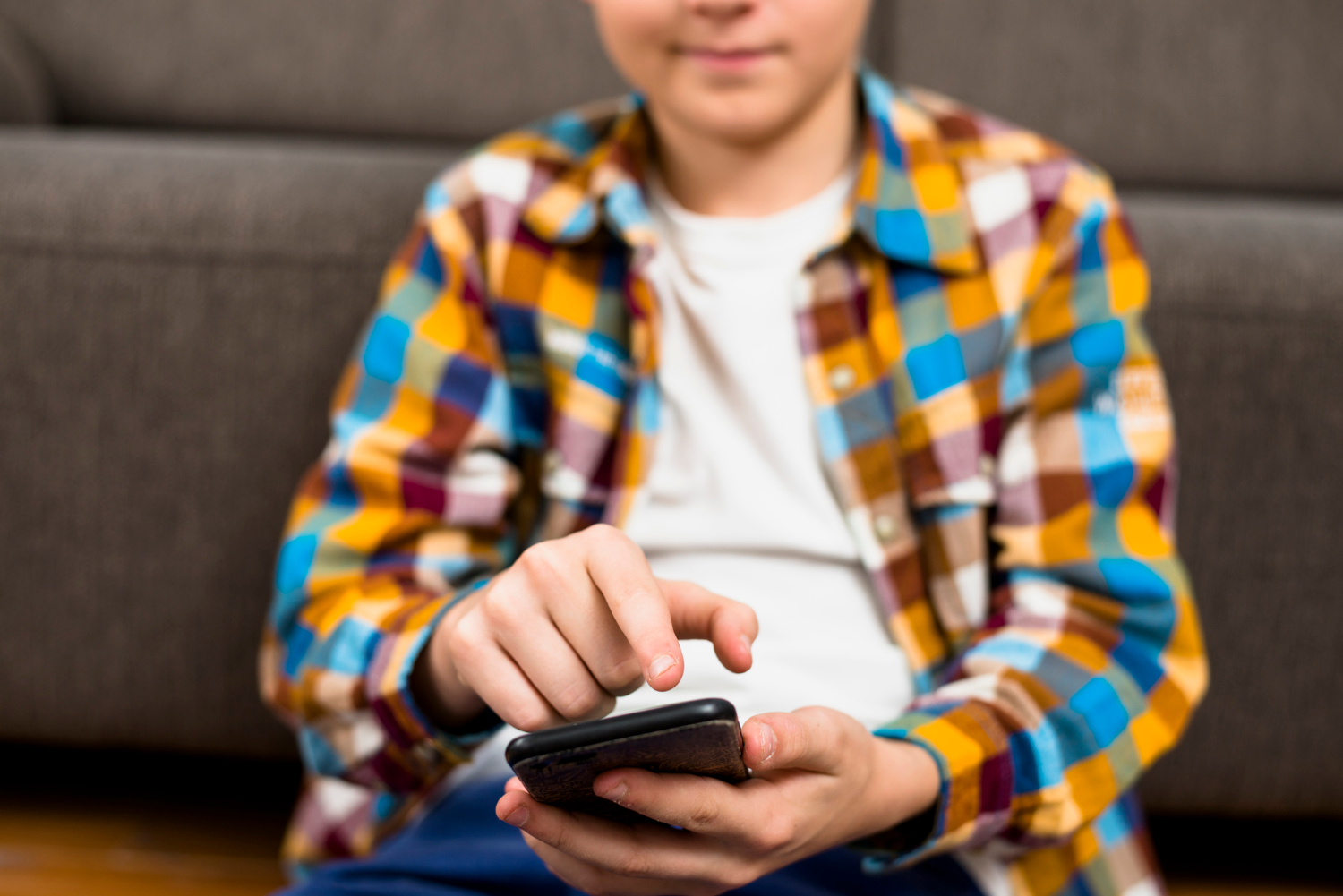 Un garçon tenant son téléphone | Source : Freepik
