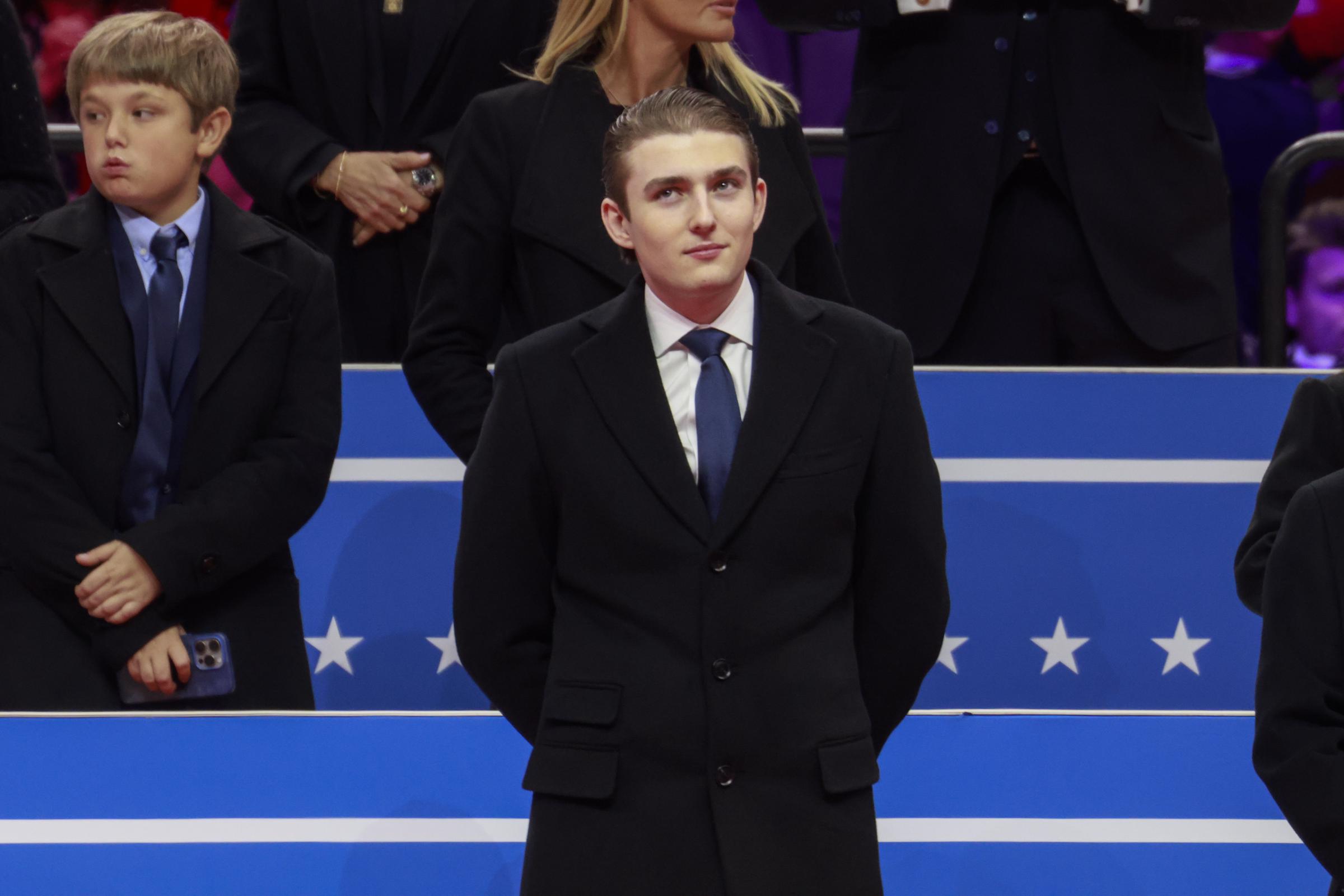 Barron Trump sourit subtilement et regarde pendant un événement d'inauguration. | Source : Getty Images