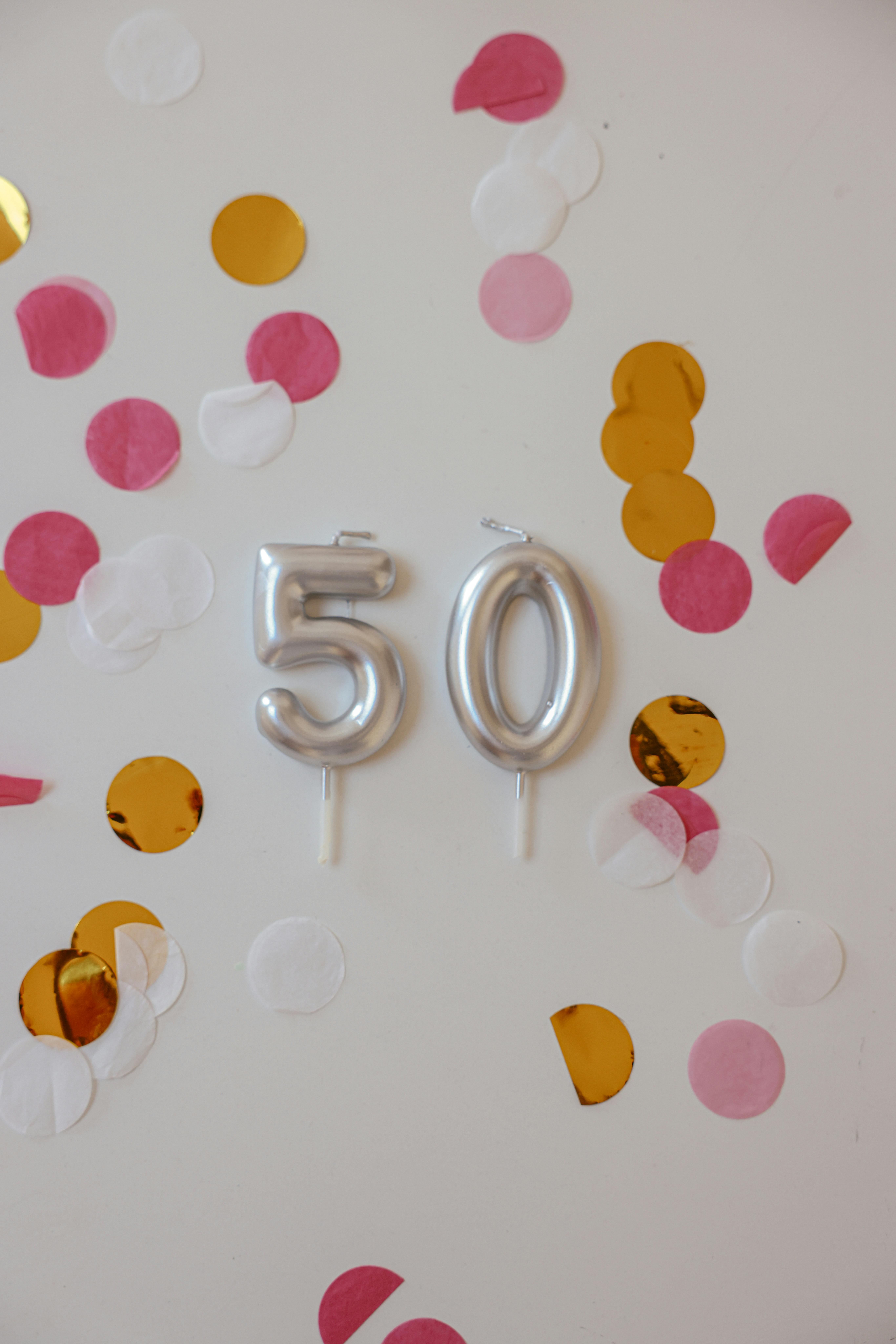 Ballons argentés et confettis colorés sur un mur | Source : Pexels