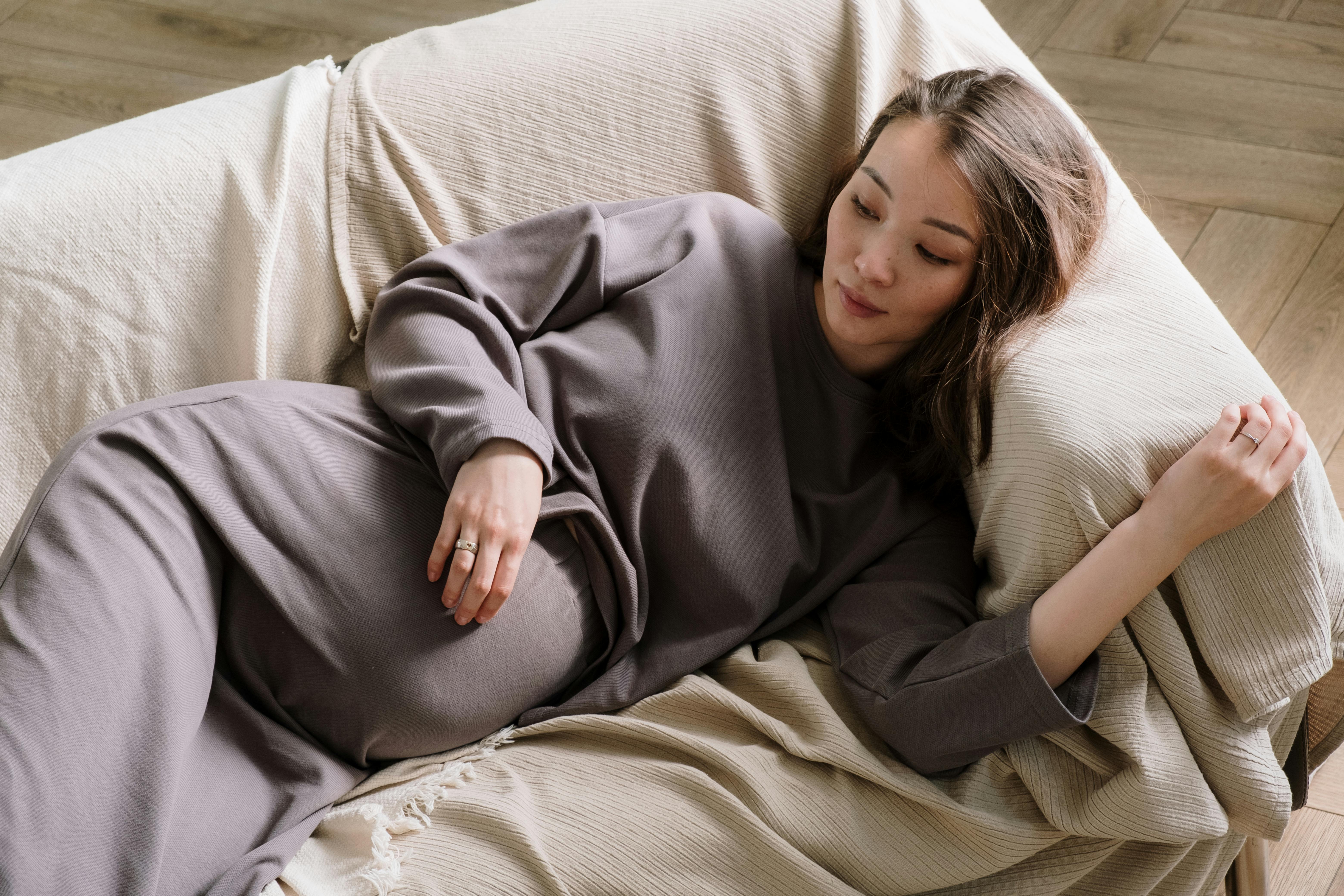 Une femme enceinte allongée sur un canapé | Source : Pexels