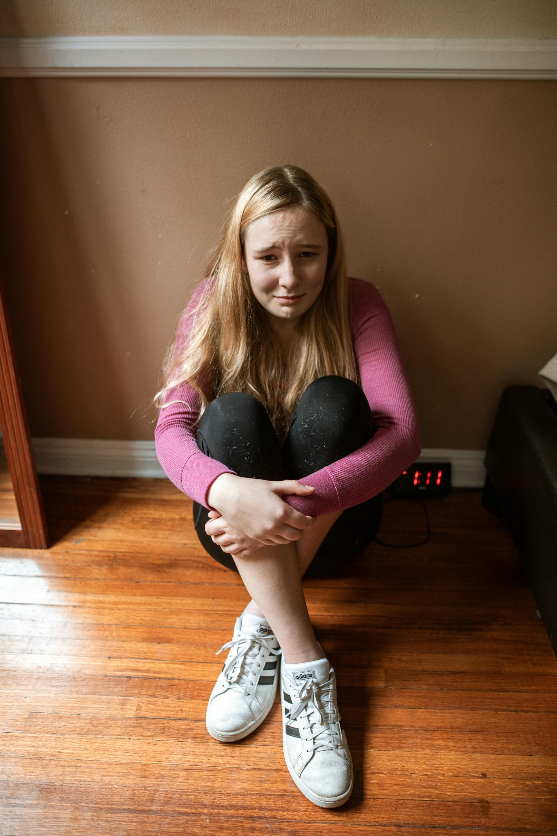 Une adolescente assise par terre et qui pleure | Source : Pexels