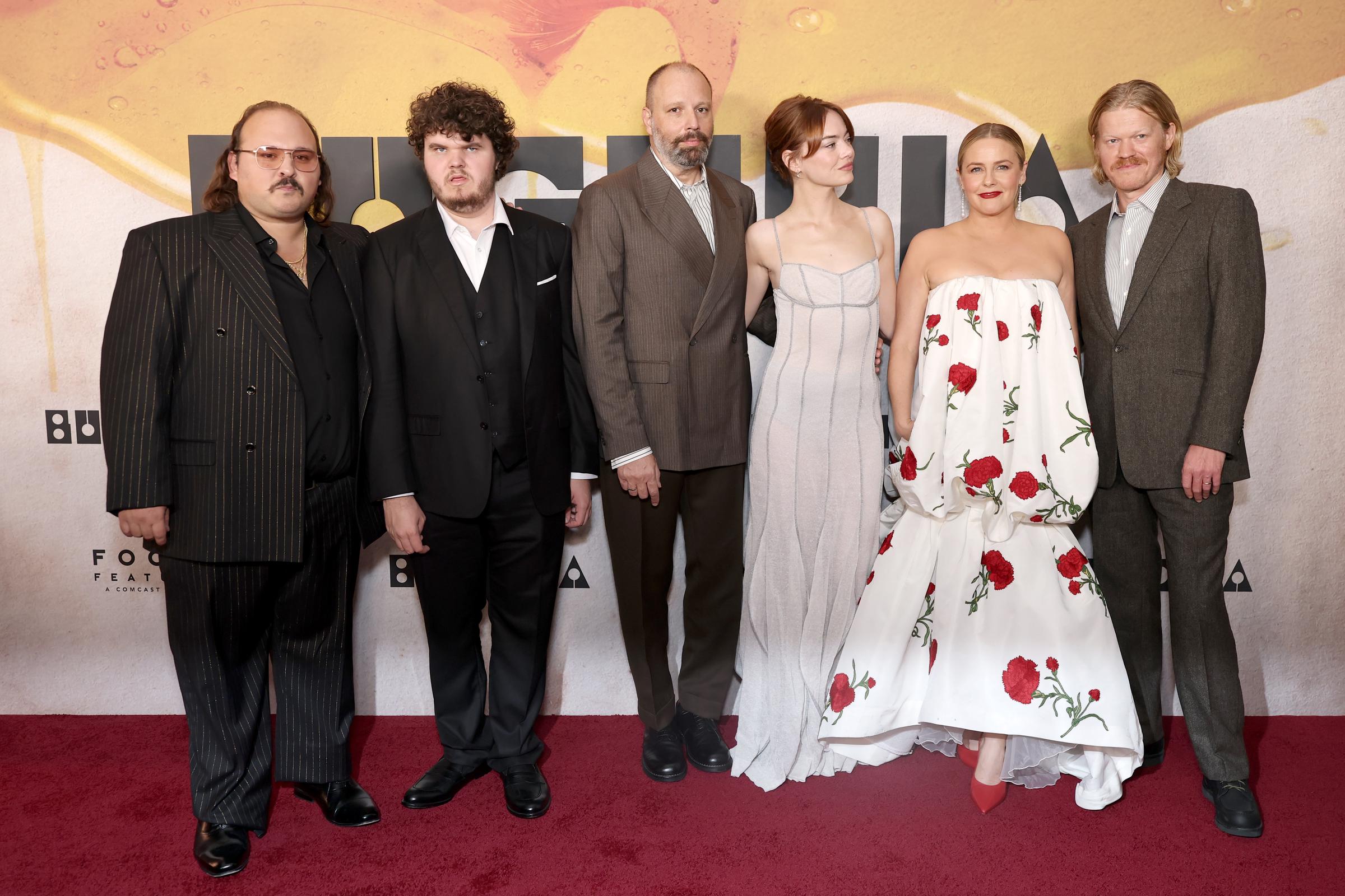 Le regard légèrement détourné de l'objectif, Emma Stone pose aux côtés de ses partenaires dans « Bugonia », Stavros Halkias, Aidan Delbis, Alicia Silverstone, Jesse Plemons et le réalisateur Yorgos Lanthimos, sa robe se démarquant parmi les tenues sur mesure du groupe.