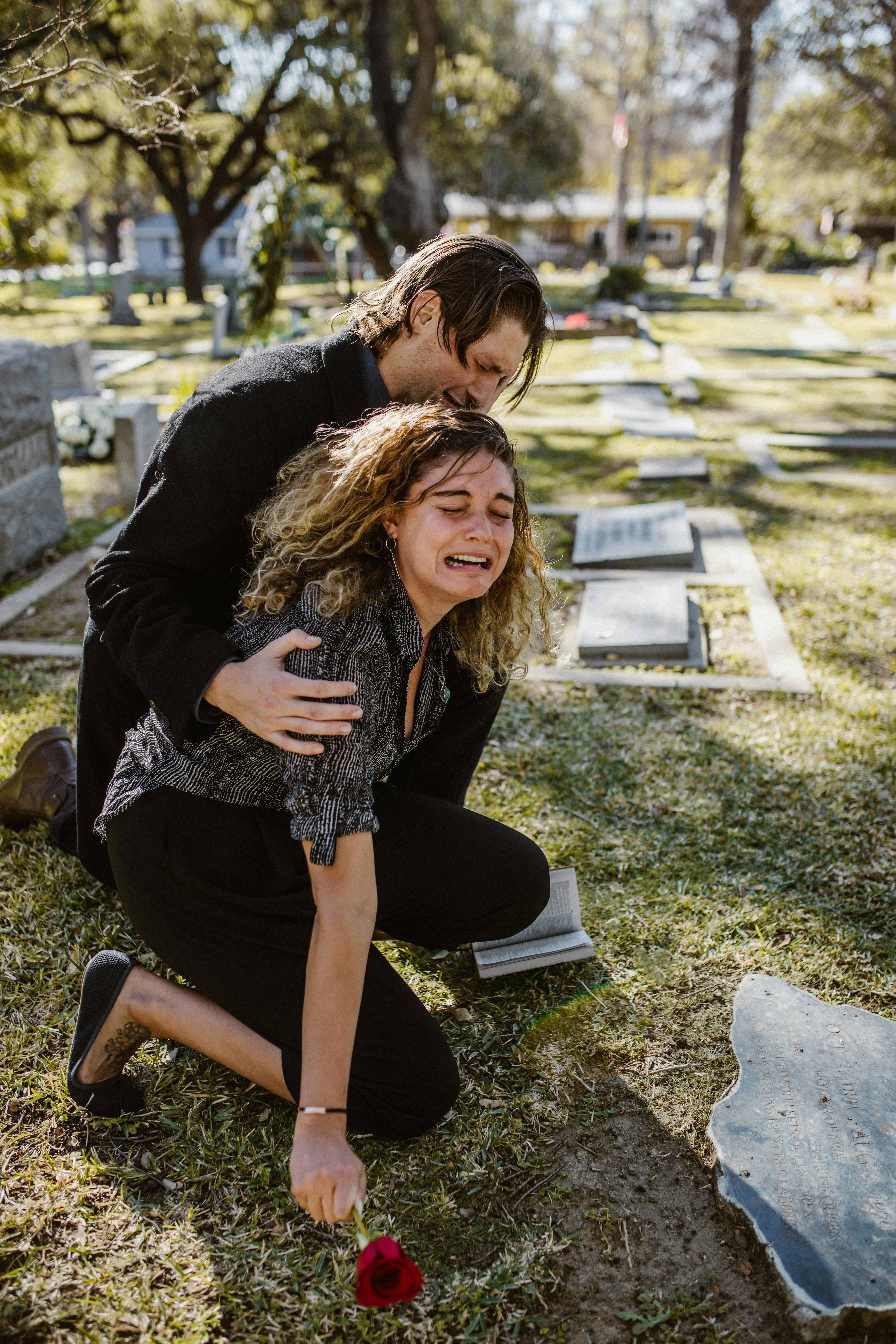 Une jeune femme réconfortée par un homme alors qu'elle pleure sur une tombe | Source : Pexels