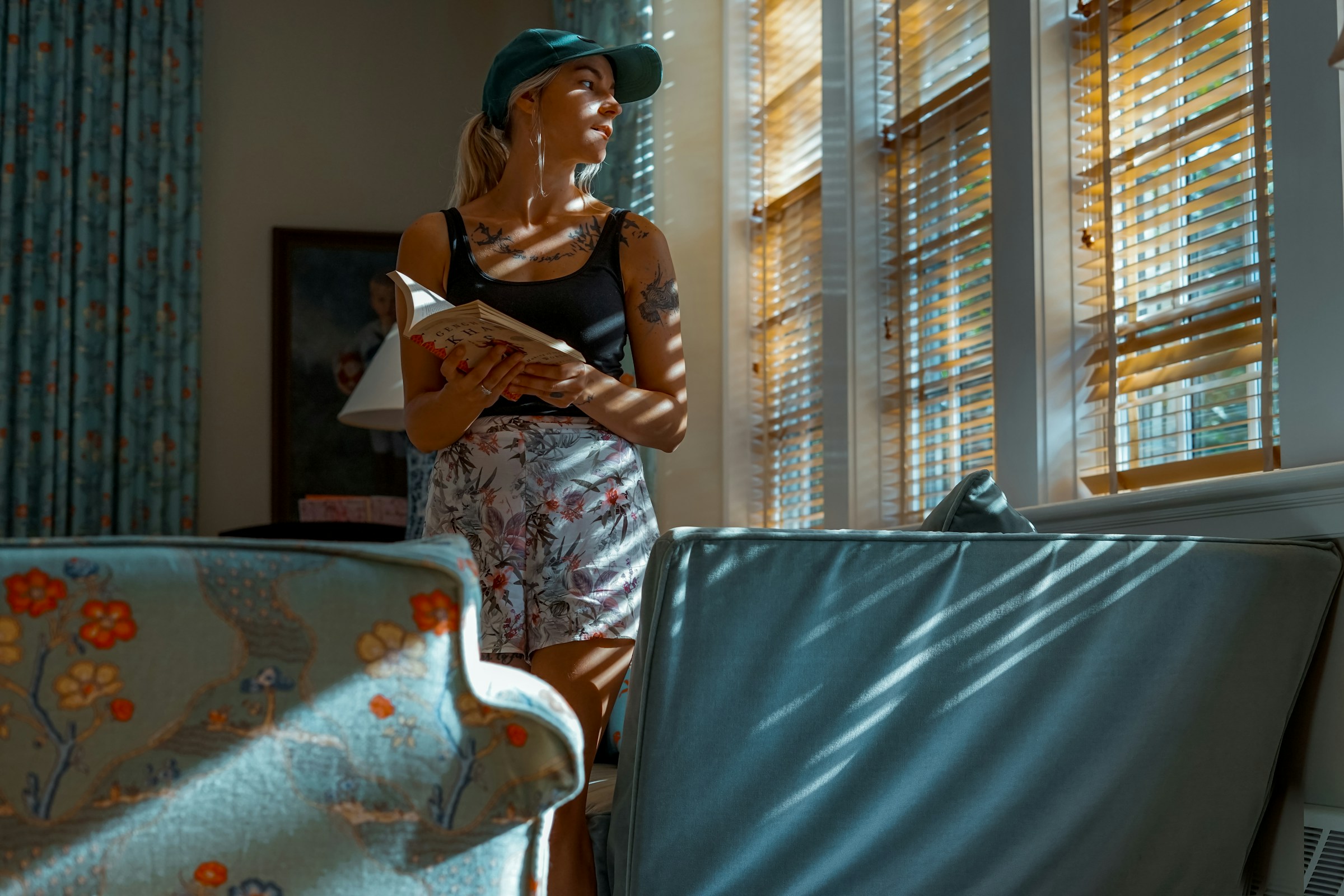 Une femme regardant par la fenêtre en tenant un livre | Source : Unsplash