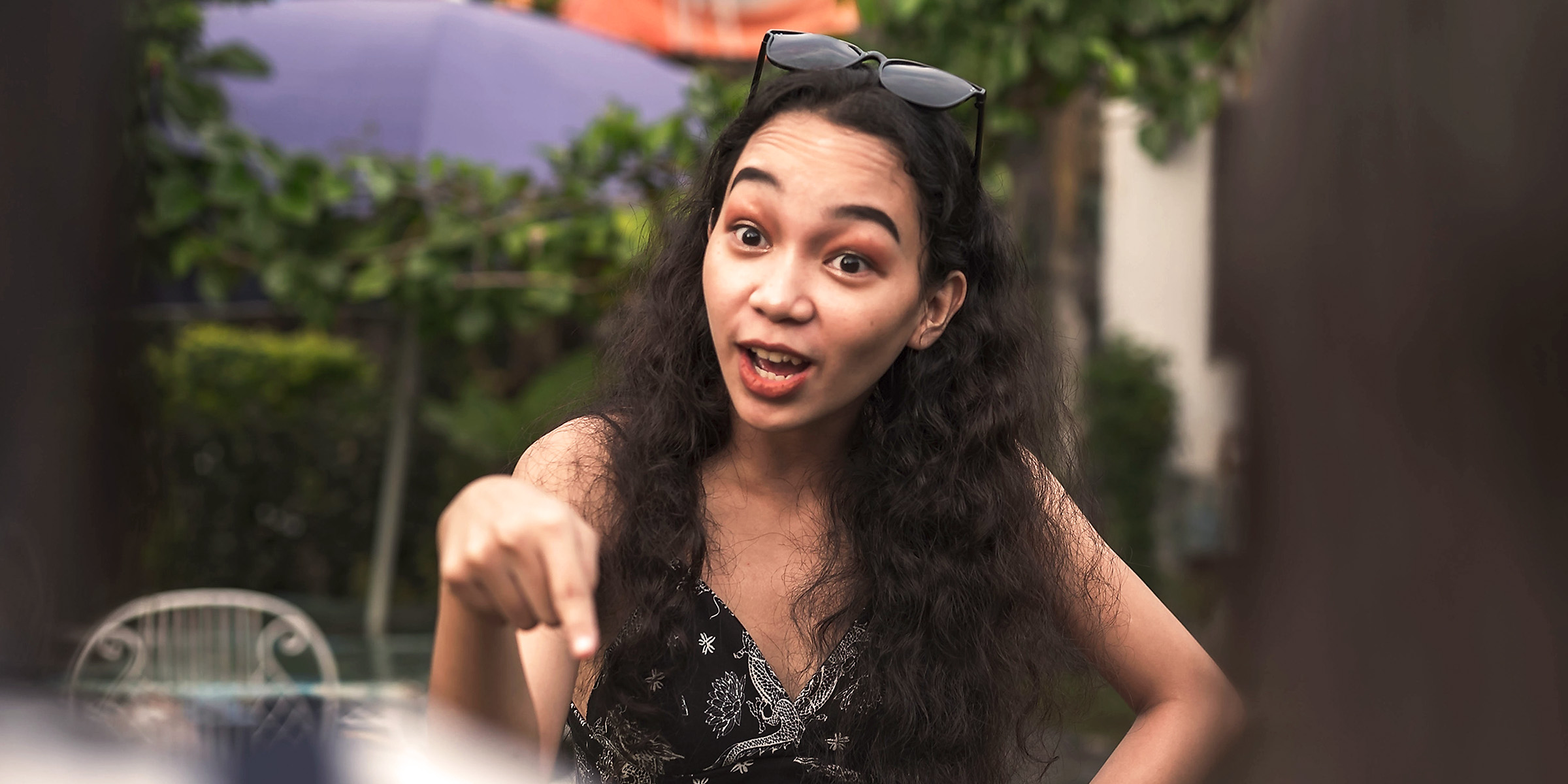 Jeune femme pointant du doigt et parlant avec une expression animée à l'extérieur | Source : Shutterstock