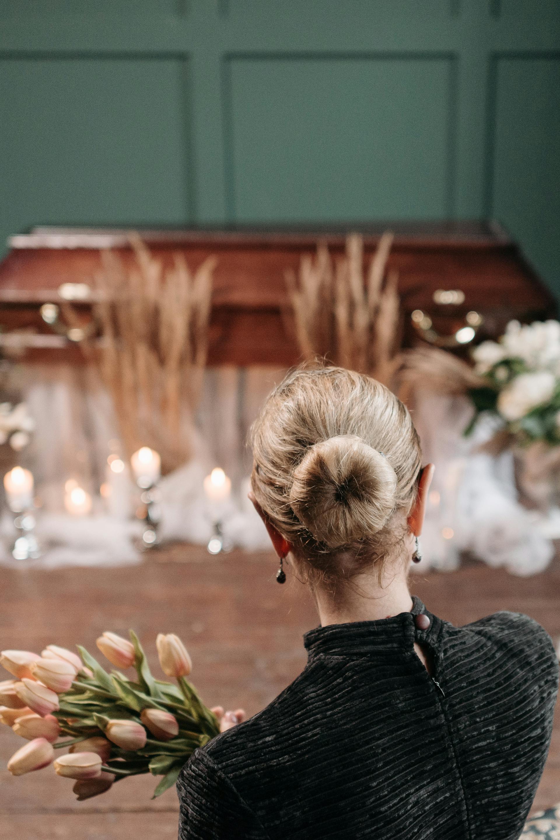 Une femme tenant un bouquet devant un cercueil | Source : Pexels