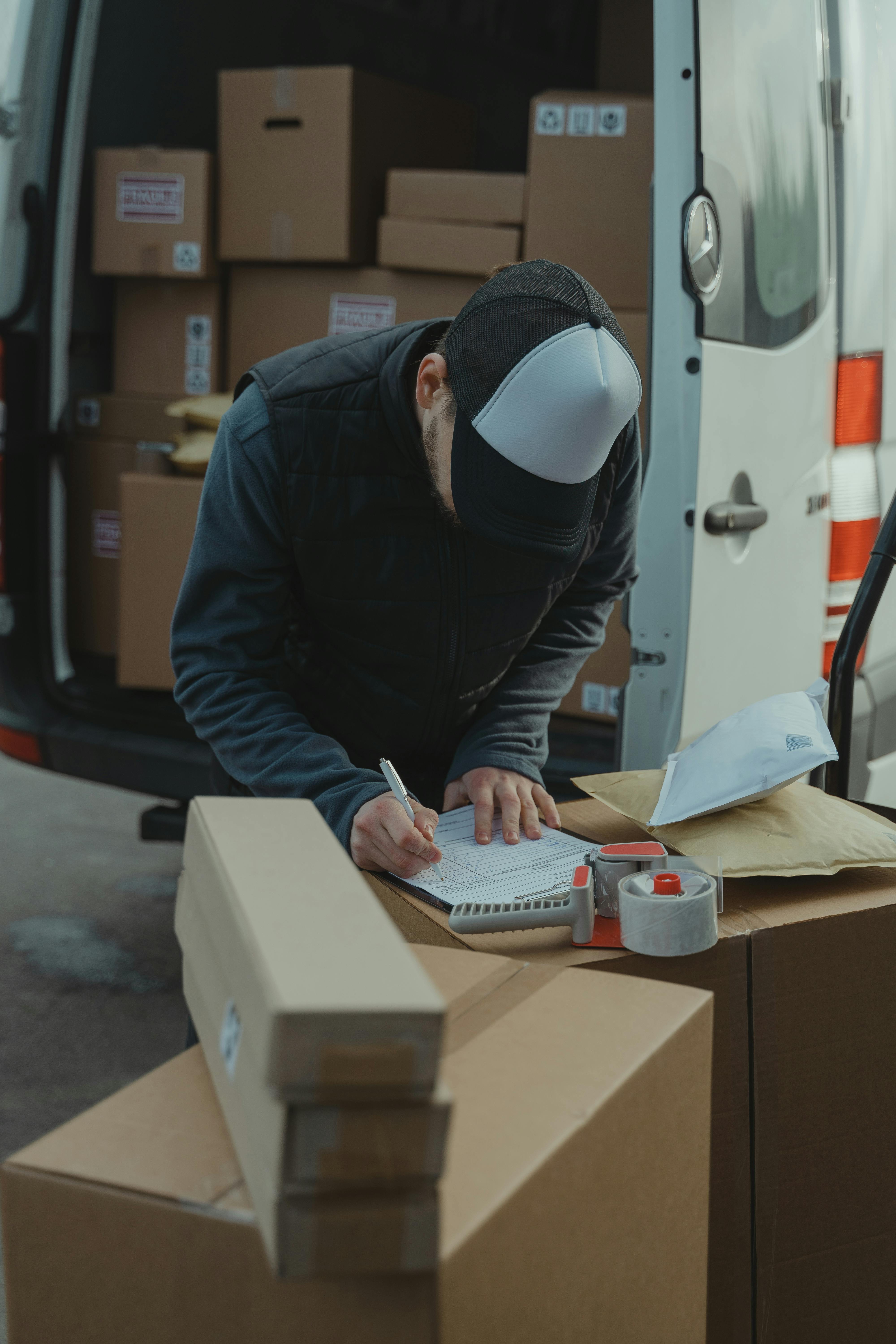 Un livreur utilisant un presse-papiers | Source : Pexels