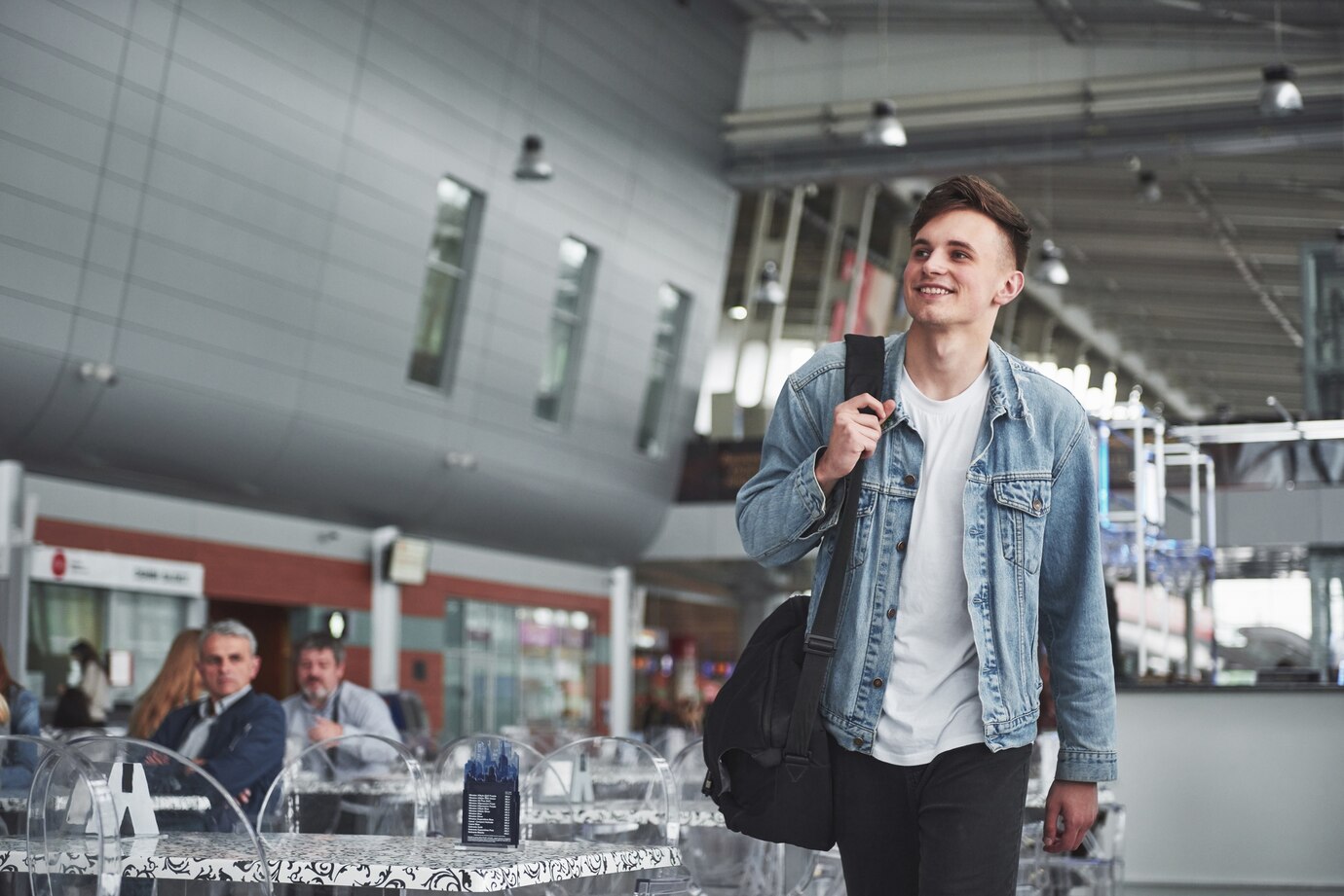 Un homme souriant marchant dans un aéroport | Source : Freepik