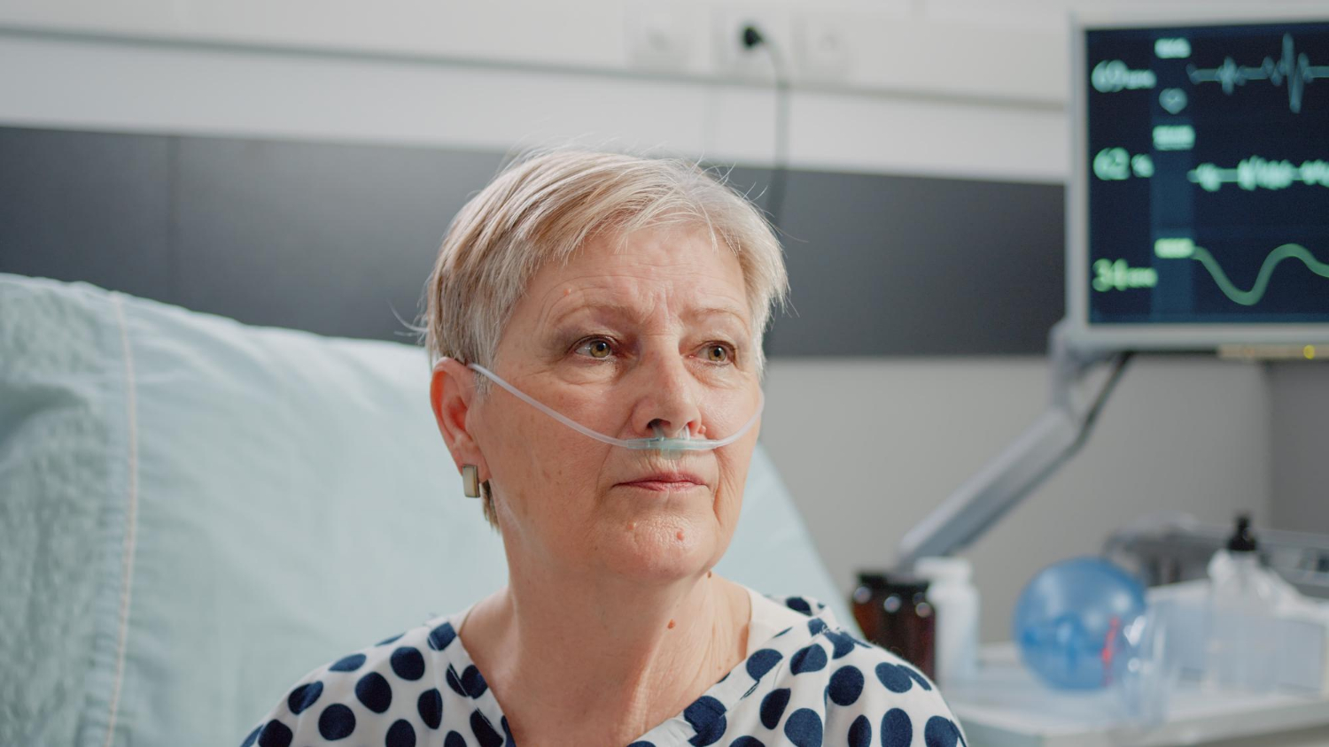 Une femme âgée assise dans une chambre d'hôpital et regardant fixement | Source : Freepik
