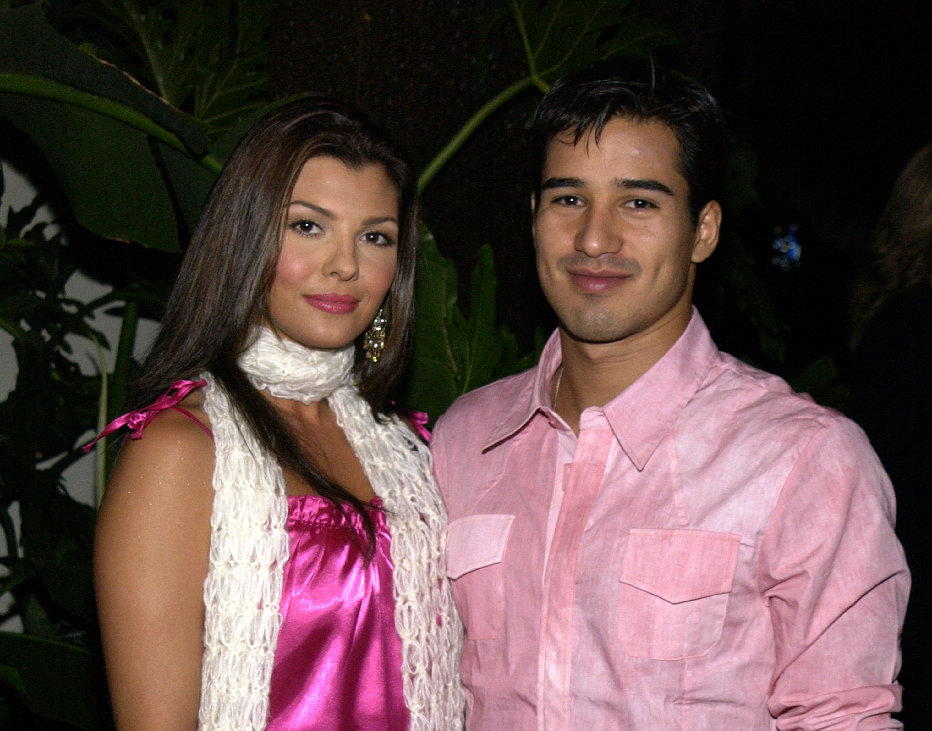 Ali Landry et Mario Lopez posent ensemble lors de la soirée de lancement d'Exclusive Artists Management à Hollywood en 2002. Landry porte un haut en satin rose vif avec un foulard blanc texturé, tandis que Lopez sourit à ses côtés dans une chemise boutonnée rose pâle.