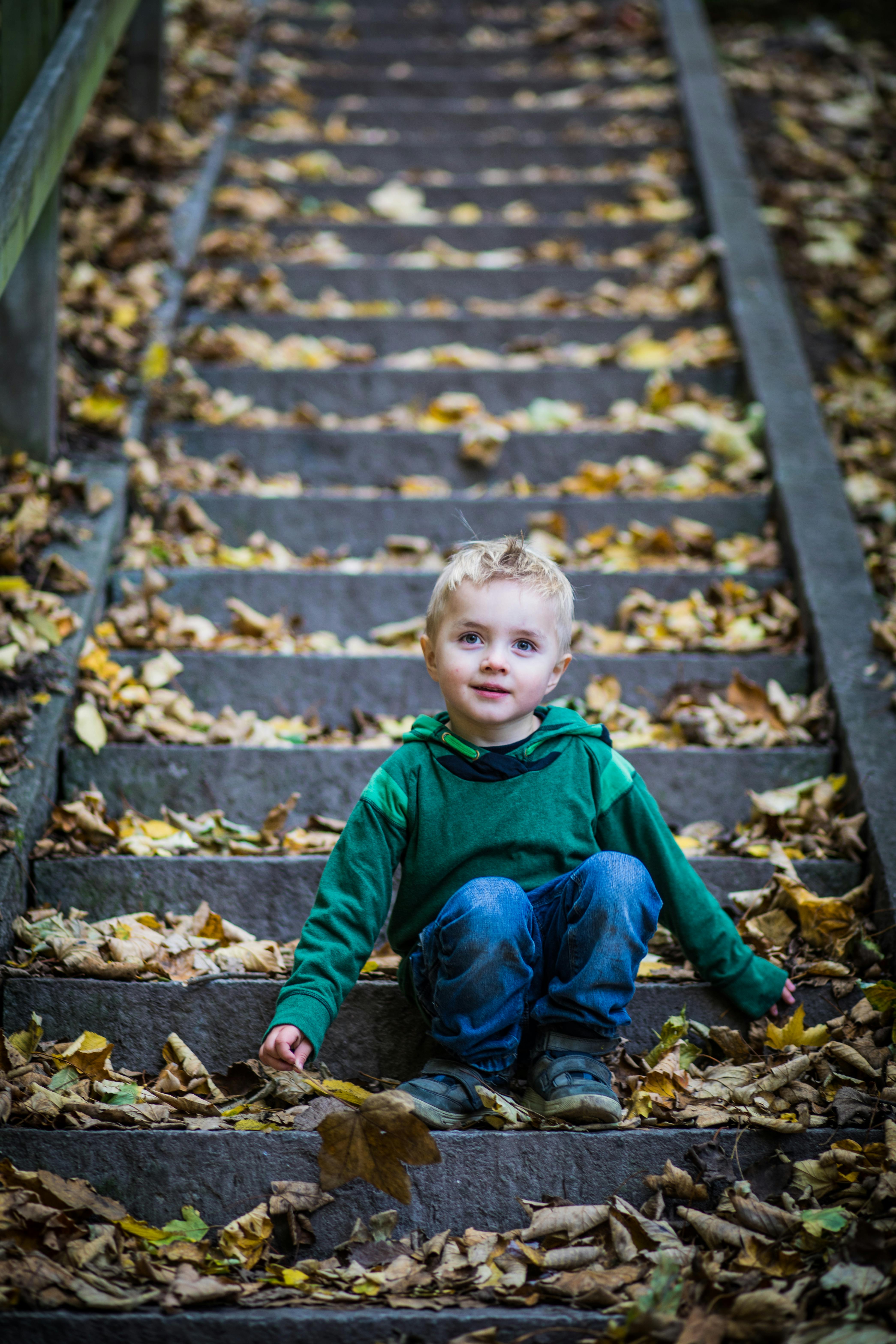 Un petit garçon assis sur un escalier | Source : Pexels