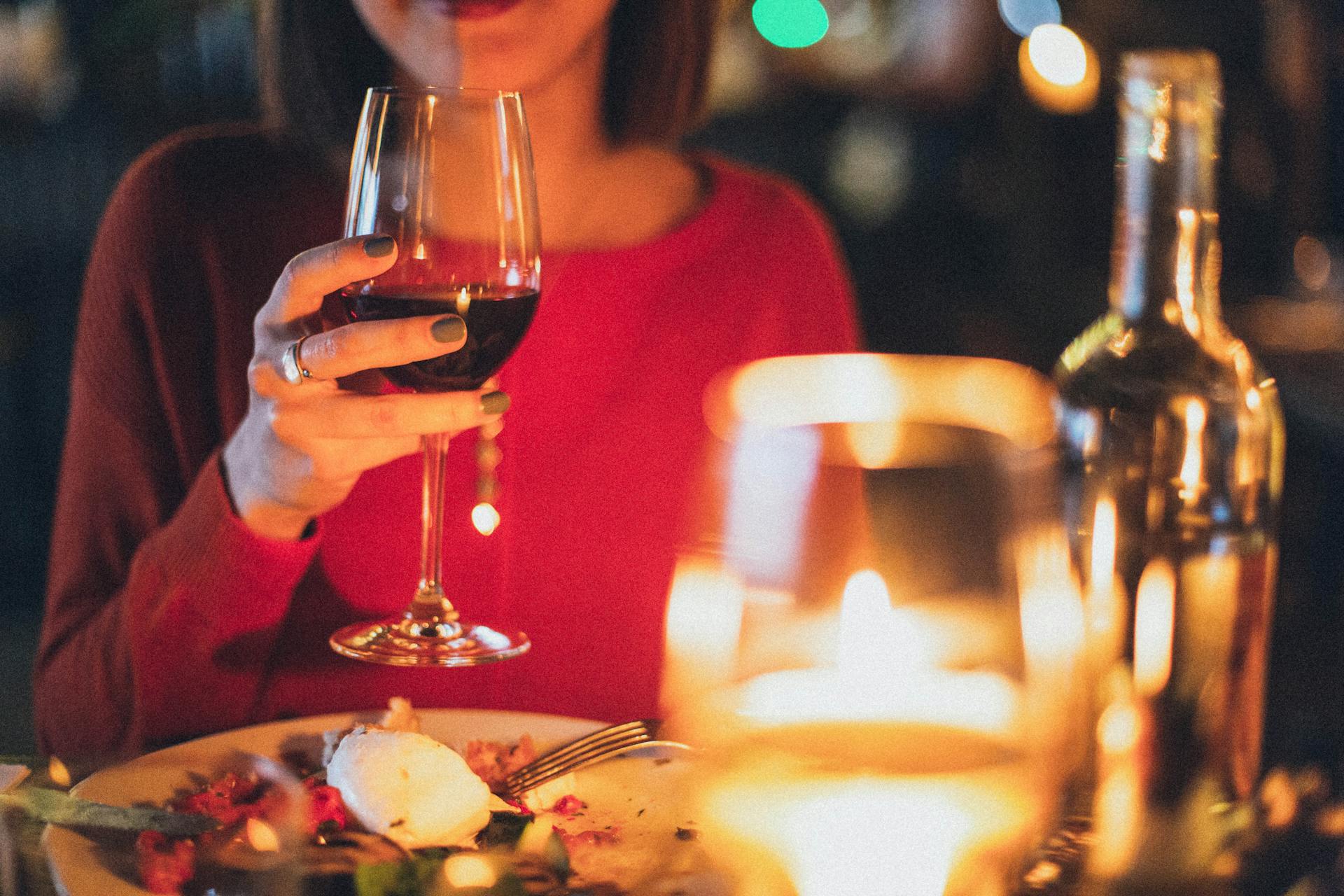 Gros plan d'une femme tenant un verre de vin pendant un dîner | Source : Pexels