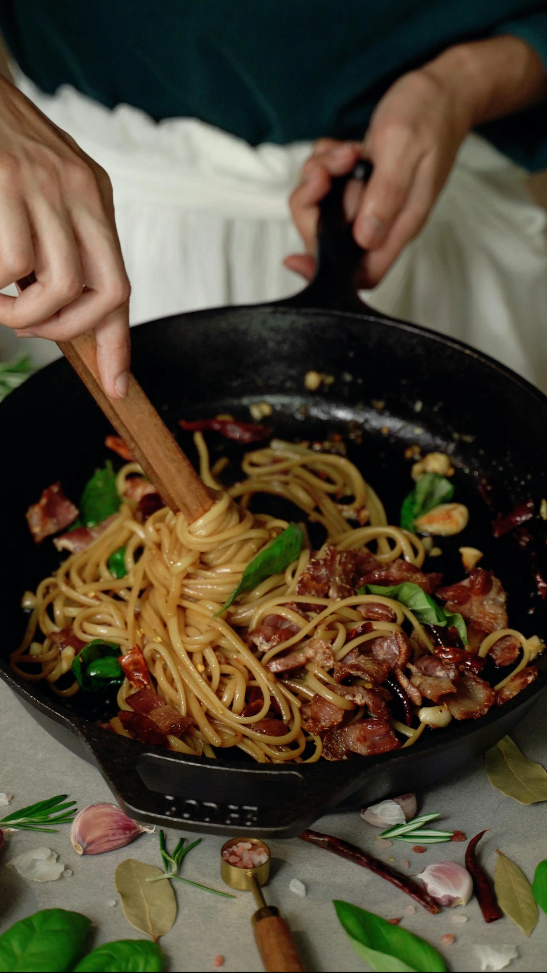 Gros plan d'une femme en train de mélanger des spaghettis dans une casserole | Source : Pexels