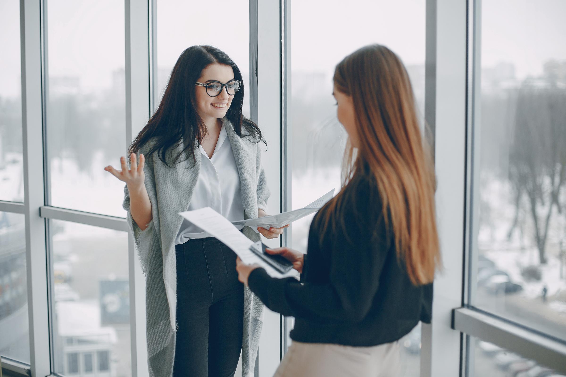 Une femme souriante qui parle à sa collègue de travail | Source : Freepik