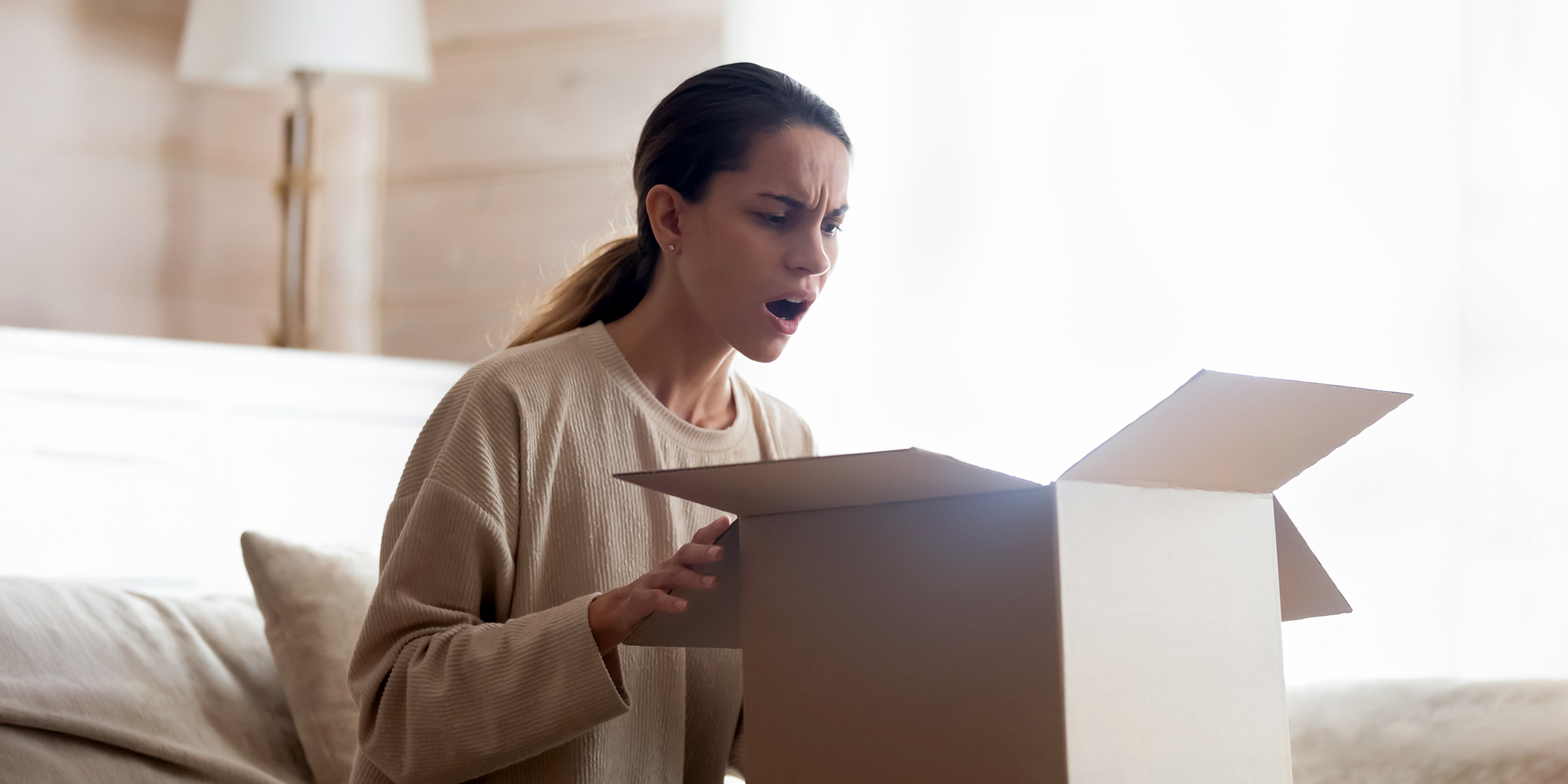 Femme ouvrant une boîte avec incrédulité | Source : Shutterstock