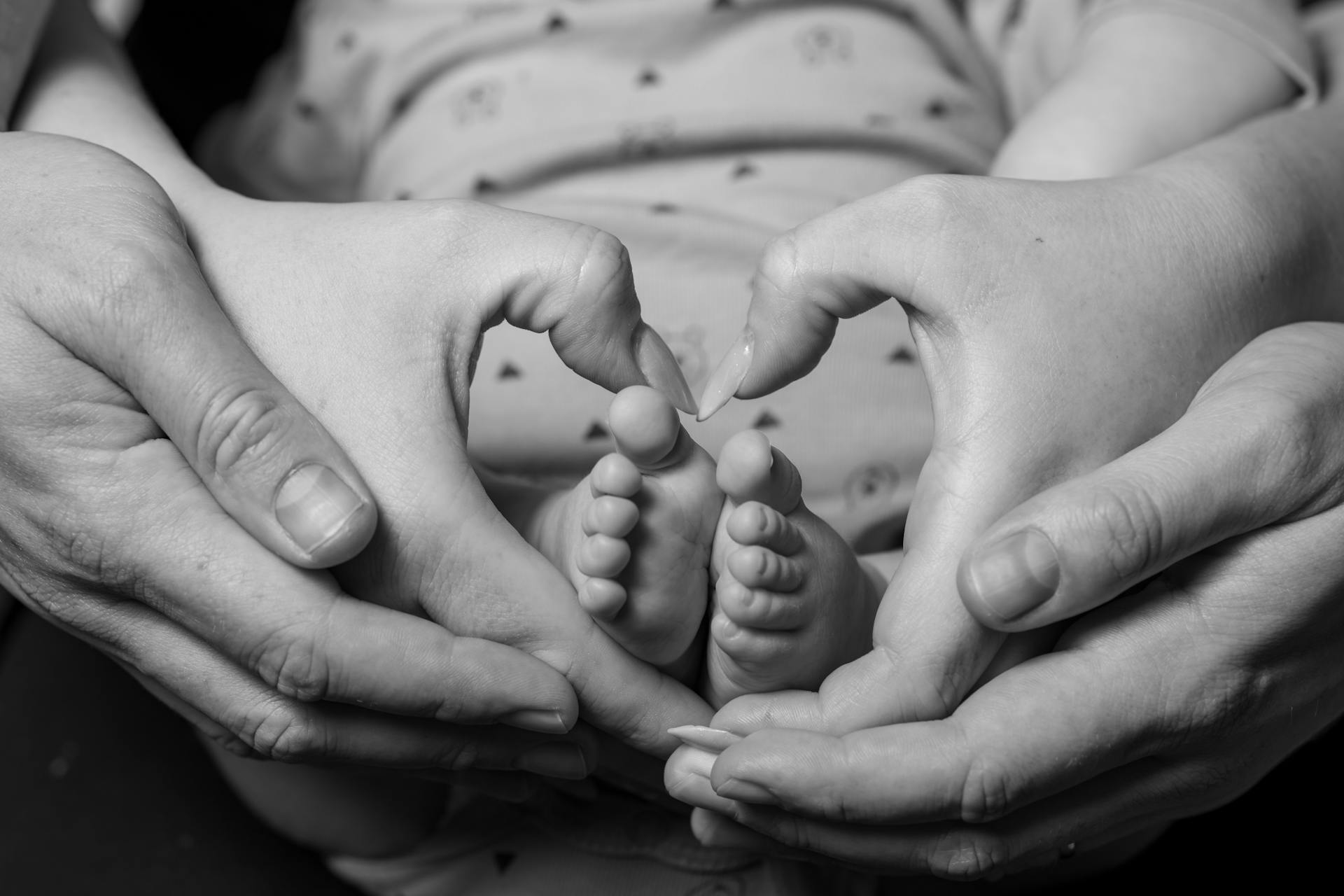 Un couple faisant un signe en forme de cœur autour des pieds de leur bébé | Source : Pexels