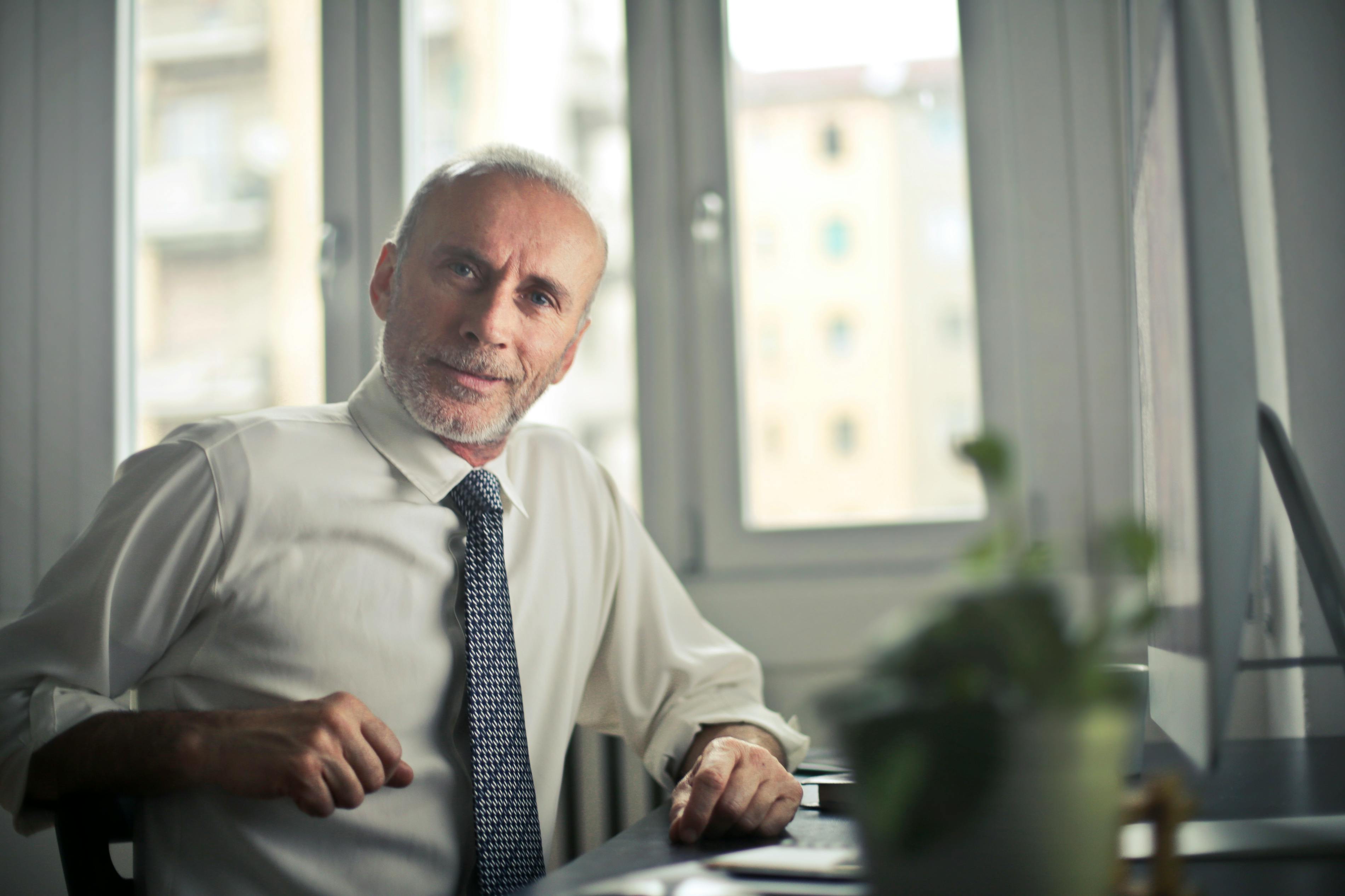 Un homme souriant assis à un bureau | Source : Pexels