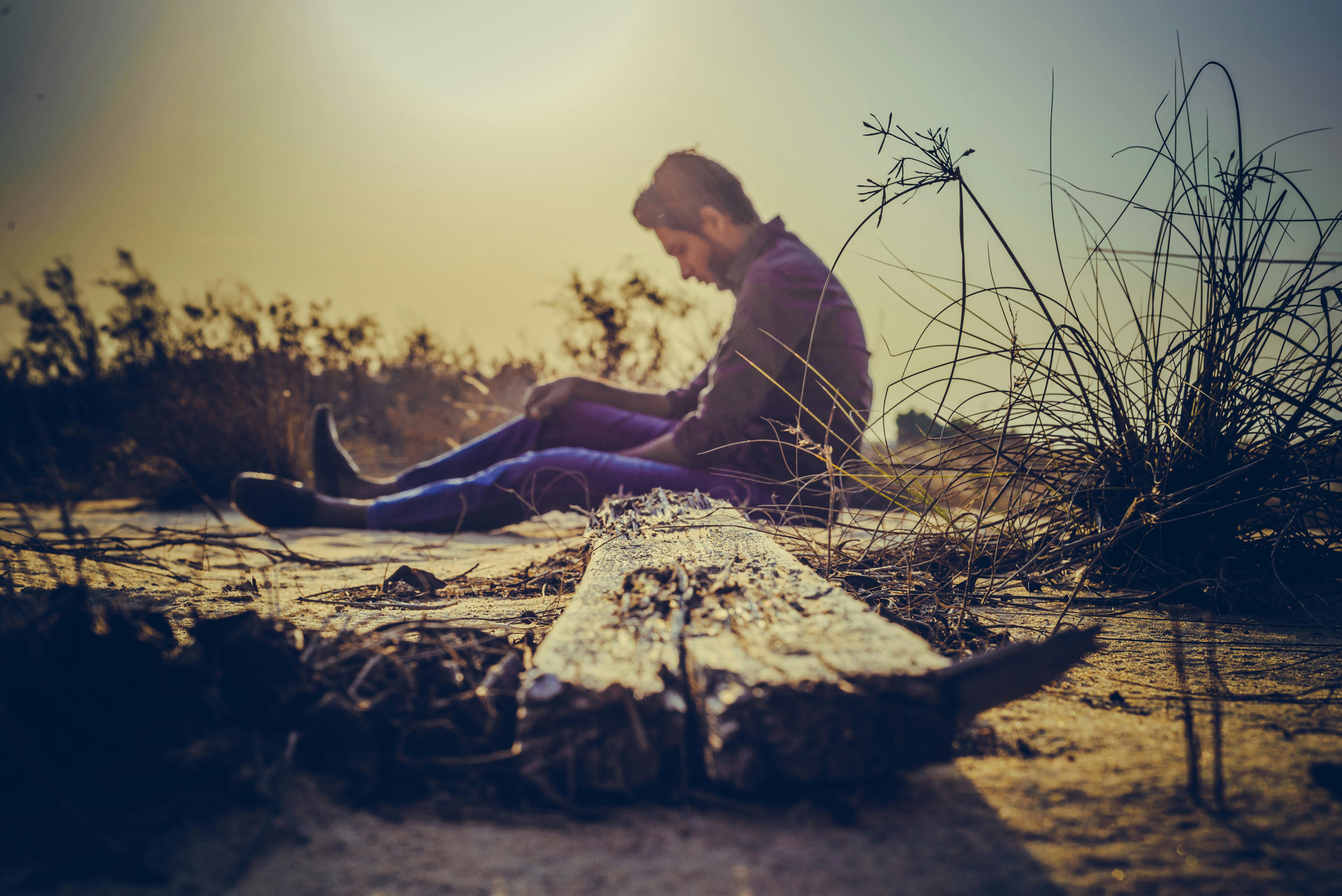 Homme triste assis sur le bord de la route | Source : Pexels