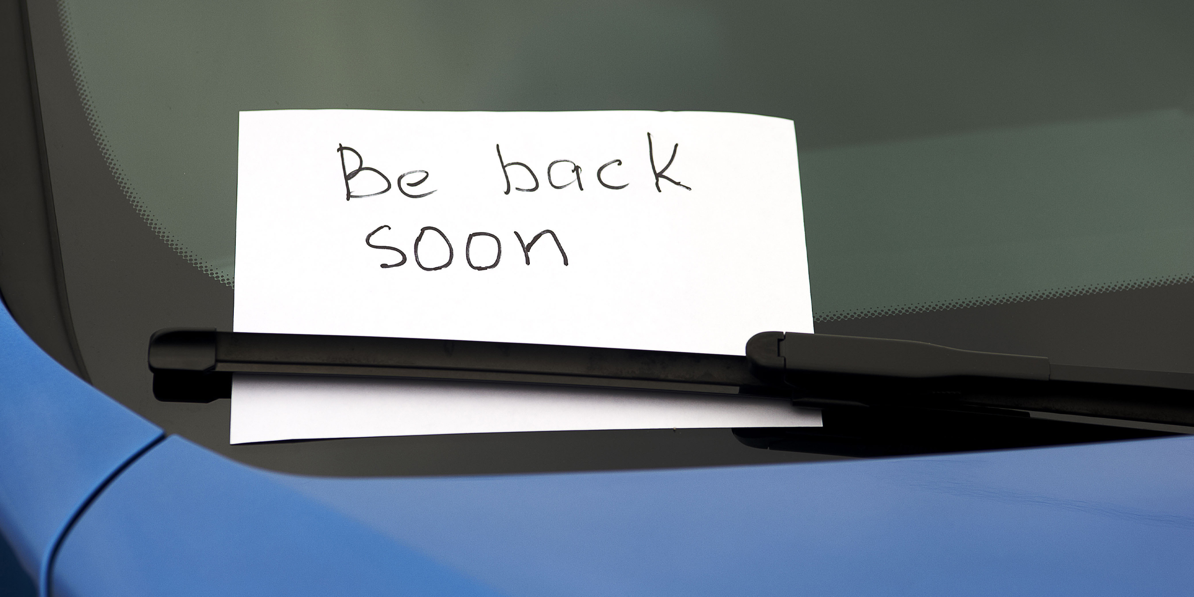 Une note manuscrite cachée sous l'essuie-glace d'une voiture | Source : Shutterstock