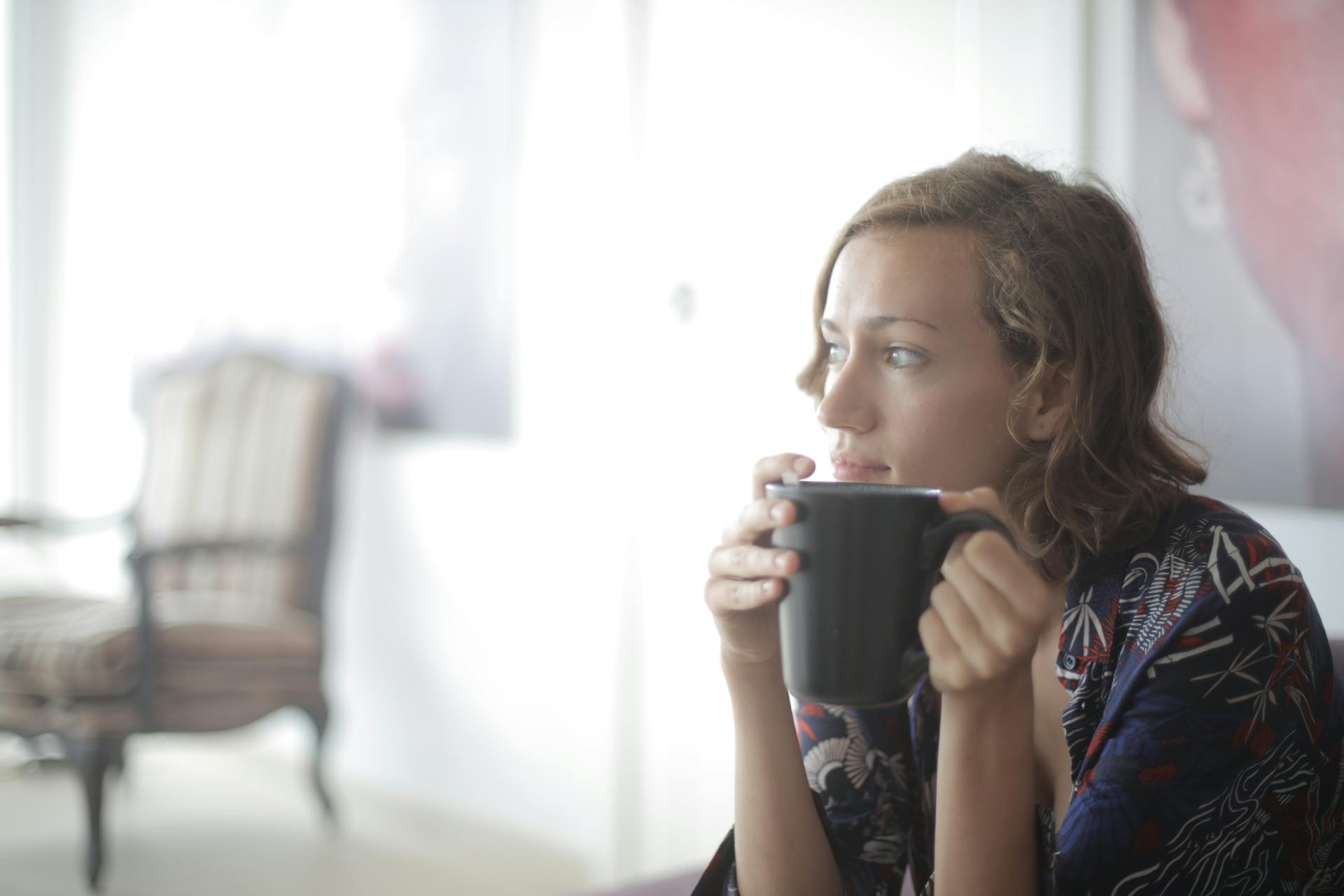 Une femme prenant une boisson chaude dans un salon | Source : Pexels
