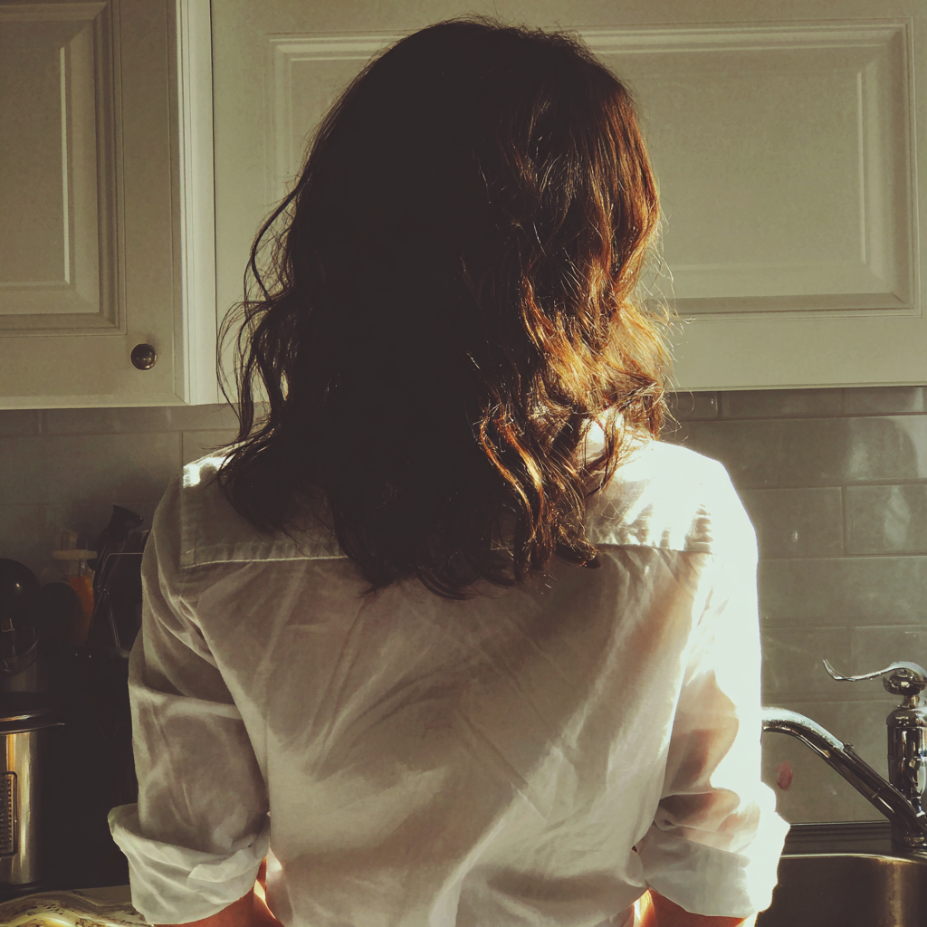 Une femme debout devant un évier de cuisine | Source : Midjourney
