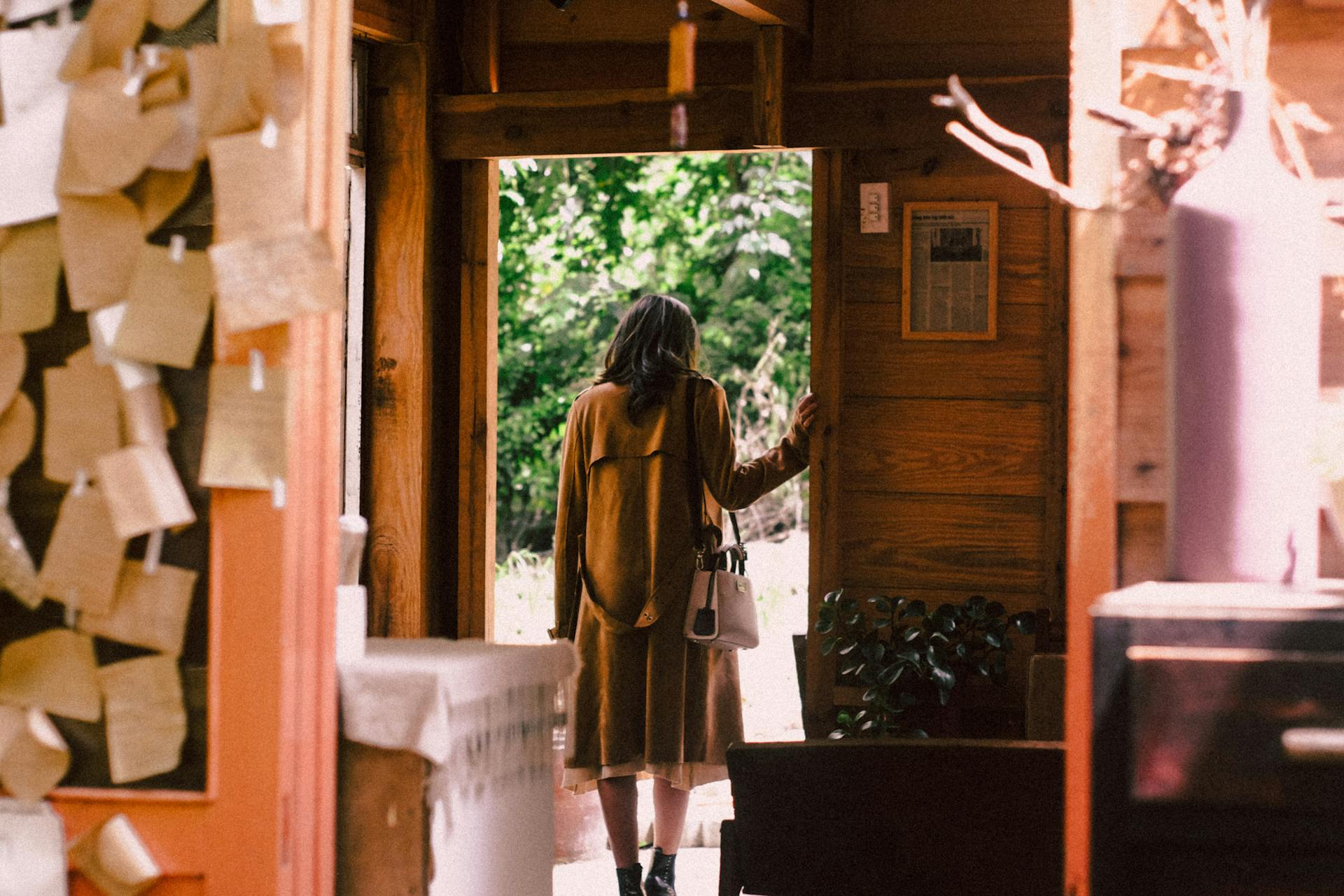 Une femme vêtue d'un long manteau en train de quitter une maison | Source : Pexels