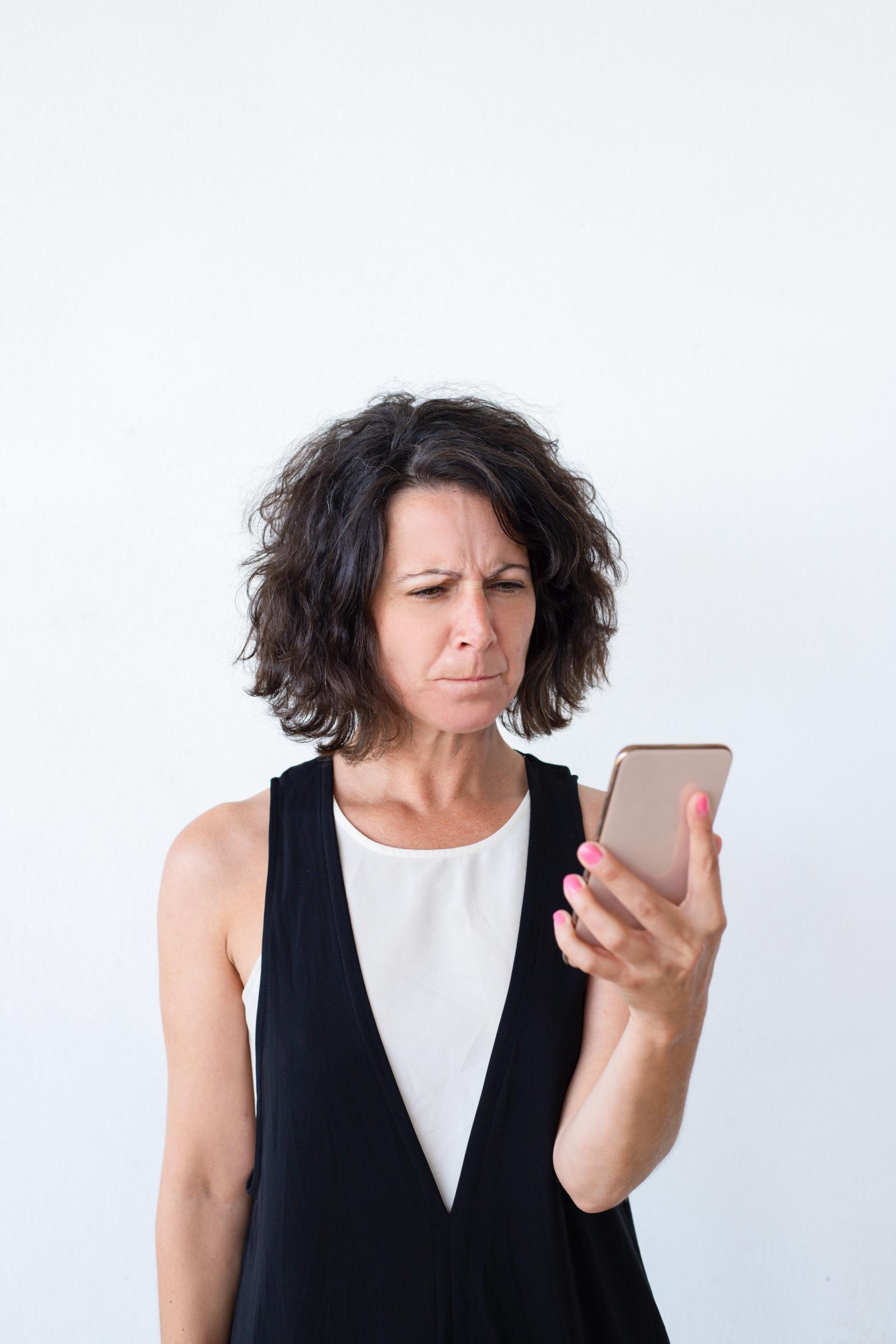 Une femme agacée qui regarde son téléphone | Source : Freepik