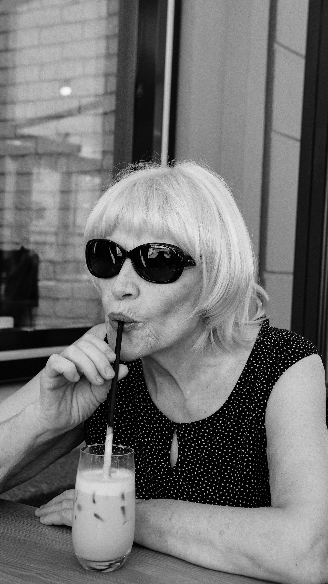 Plan en niveaux de gris d'une femme âgée buvant un verre de boisson | Source : Pexels