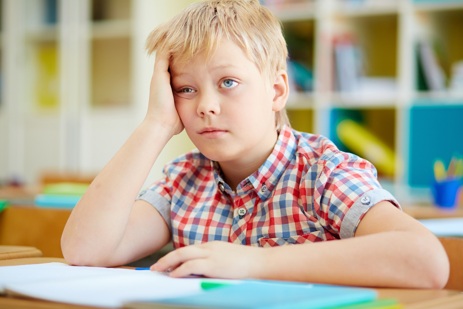 Un garçon triste assis à un bureau | Source : Freepik