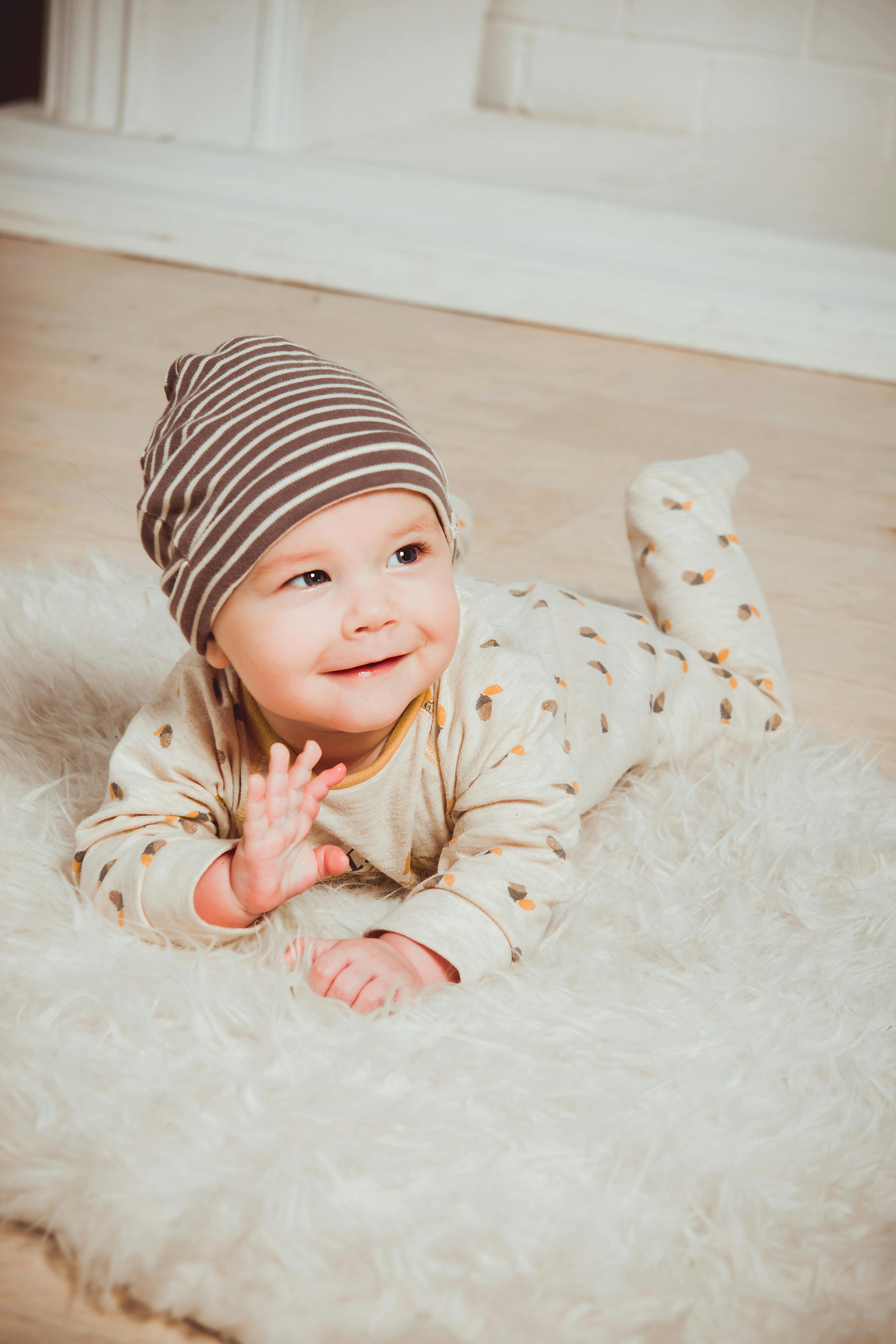 Un bébé souriant sur un tapis blanc | Source : Pexels