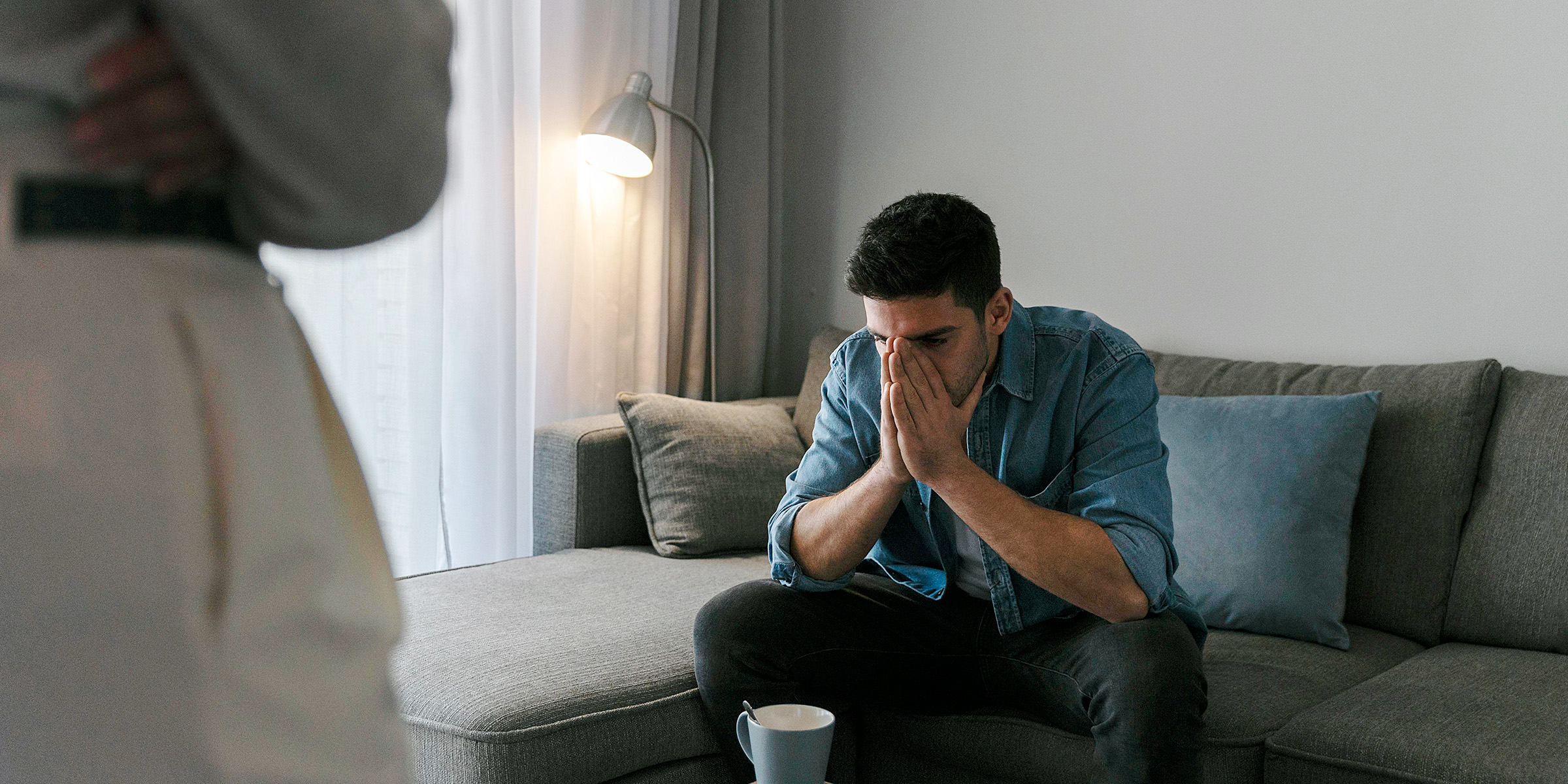 Un homme assis sur un canapé avec ses mains sur son visage | Source : Freepik