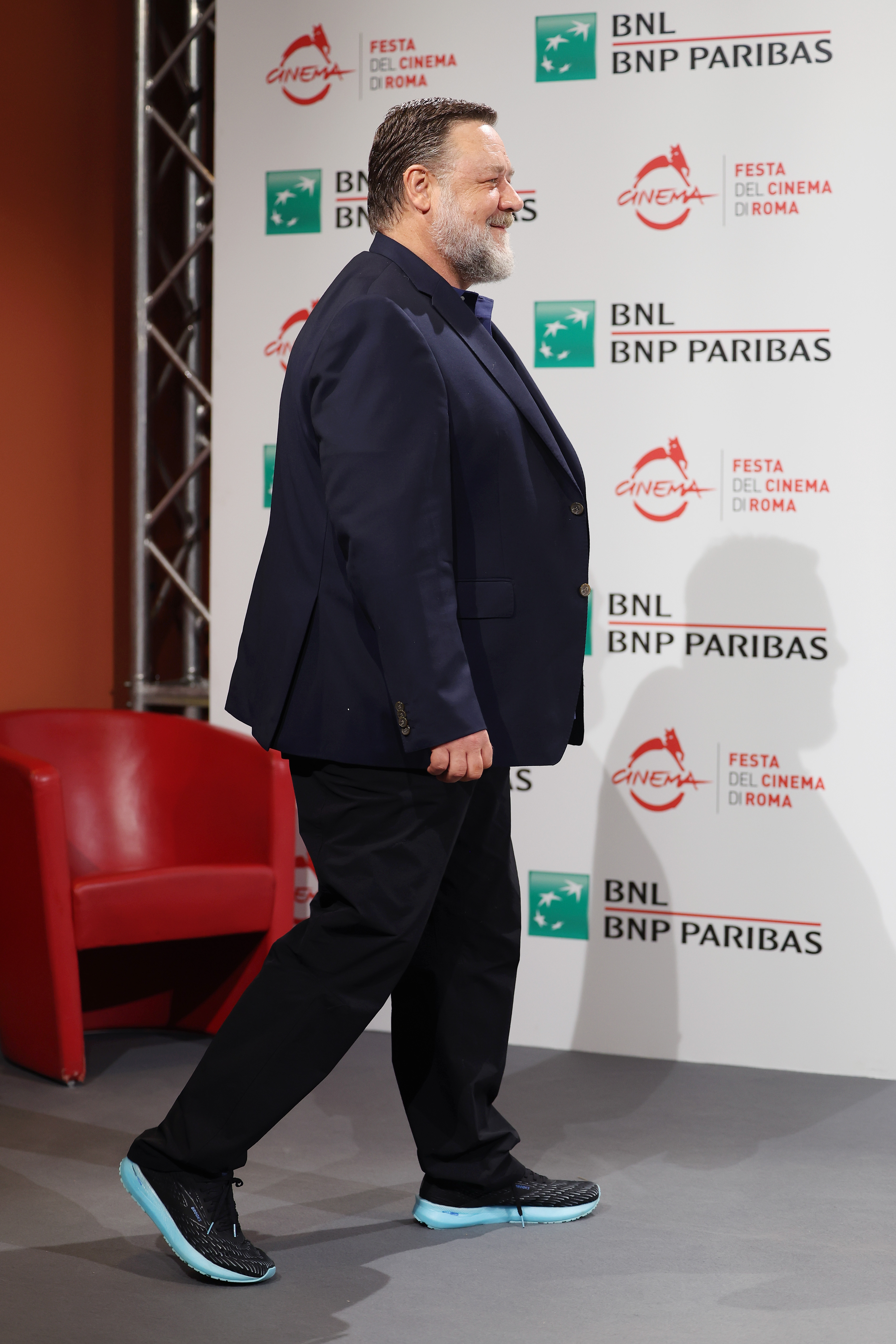 Russell Crowe participe à la séance photo « Poker Face » lors du 17e Festival du film de Rome, le 16 octobre 2022, en Italie, vêtu d'un blazer bleu marine et de baskets à semelles colorées. Souriant tandis qu'il marchait, il semblait plus corpulent avant de commencer le régime santé rigoureux qui allait entraîner un changement physique spectaculaire.