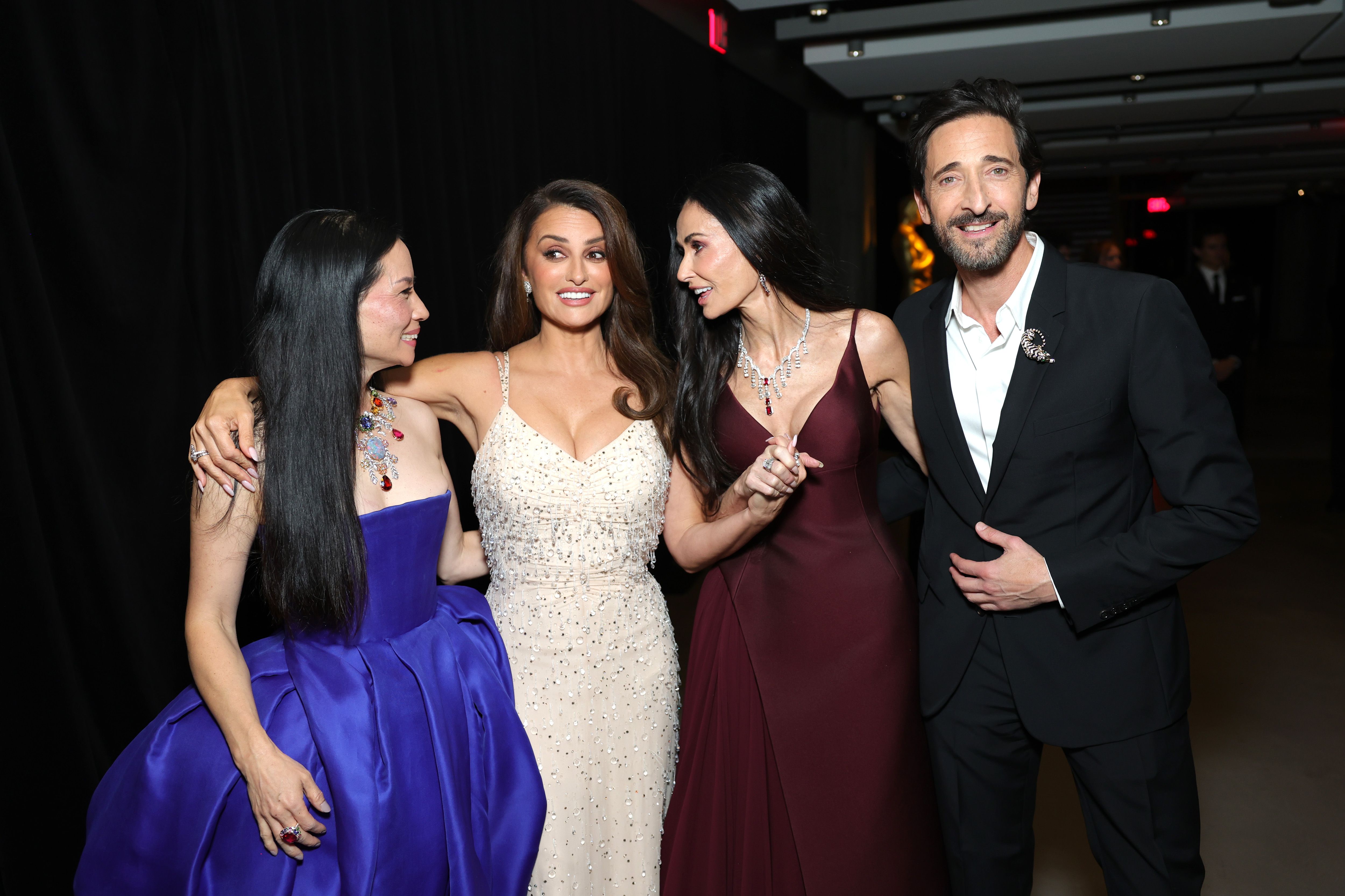Bras dessus bras dessous avec Lucy Liu et Penélope Cruz, Demi Moore rit au milieu d'une conversation alors qu'elles saluent Adrien Brody — un cliché spontané et prestigieux qui témoigne de la complicité et du charisme qui règnent sur le tapis rouge du gala.
