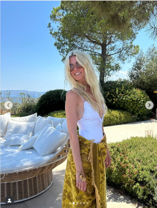 Claudia Schiffer rayonne d'élégance le jour de son anniversaire, posant dans un haut blanc chic et un châle à motifs dorés devant un décor extérieur serein. Avec ses cheveux illuminés par le soleil et son sourire joyeux, elle célèbre une beauté et une grâce intemporelles | Source : Instagram/claudiaschiffer