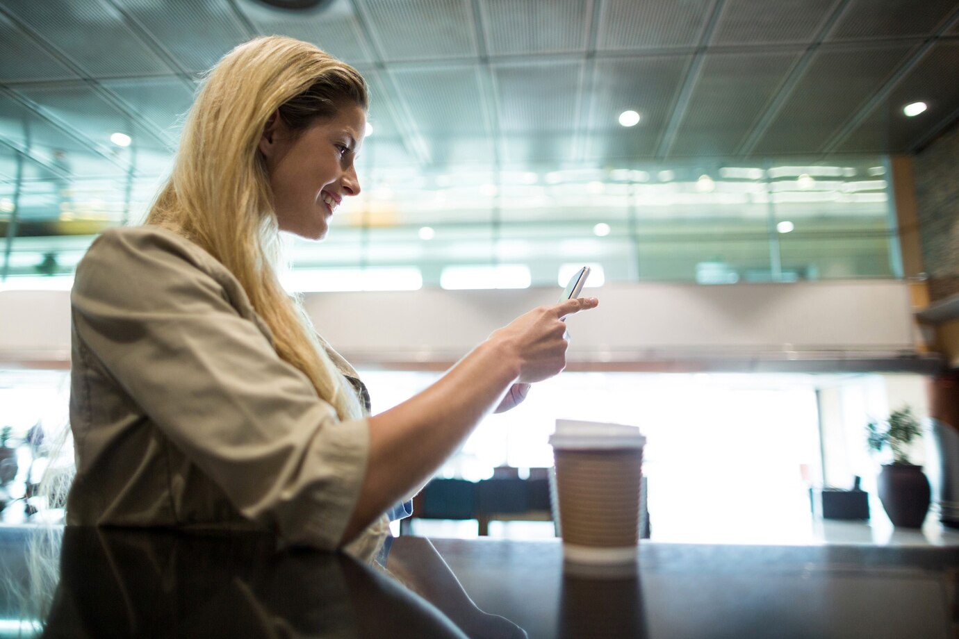 Une femme sur son téléphone dans un aéroport | Source : Freepik