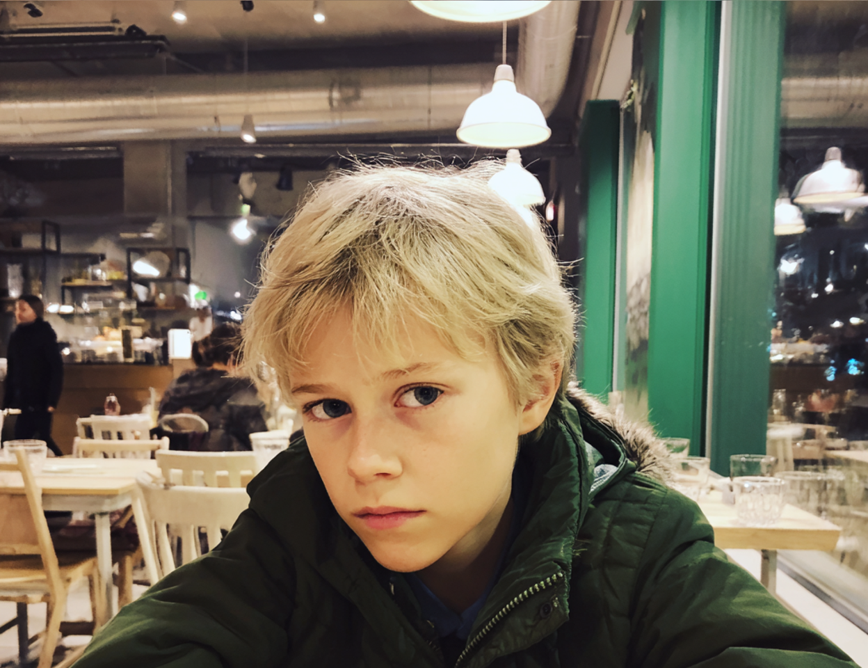 Gros plan d'un garçon assis à une table | Source : Midjourney