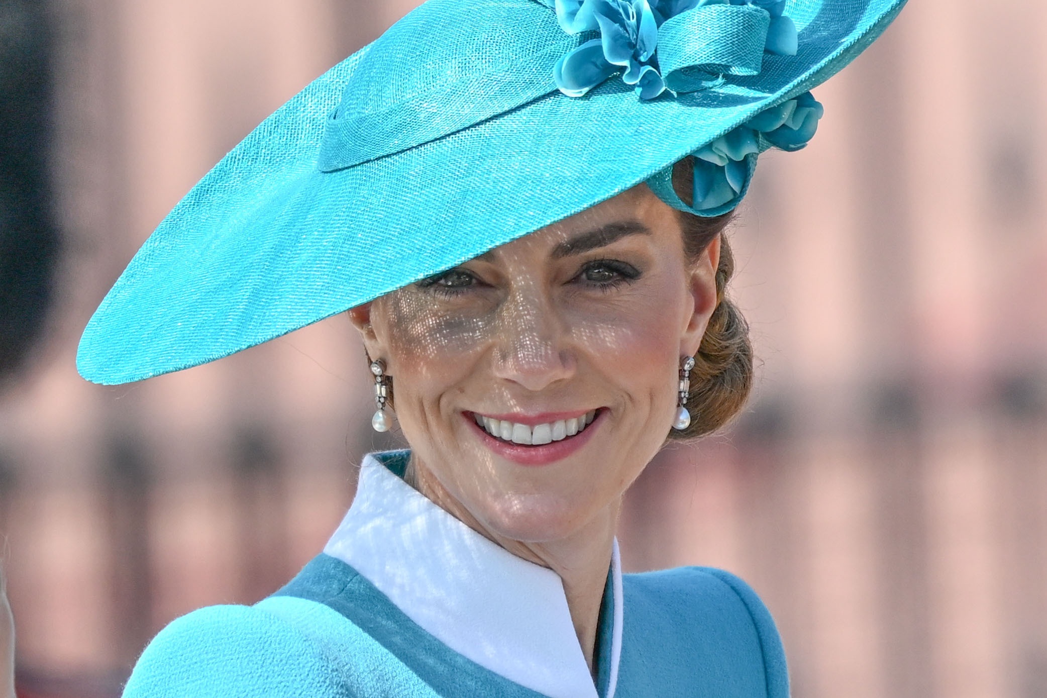 Sur un gros plan pris lors de la parade Trooping the Colour de 2025, la princesse Catherine rayonne d'un sourire chaleureux. La photo capture son visage dans ses moindres détails, encadré par un élégant chapeau bleu sarcelle orné de fleurs, une image de grâce et de confiance au cœur de la célébration royale.